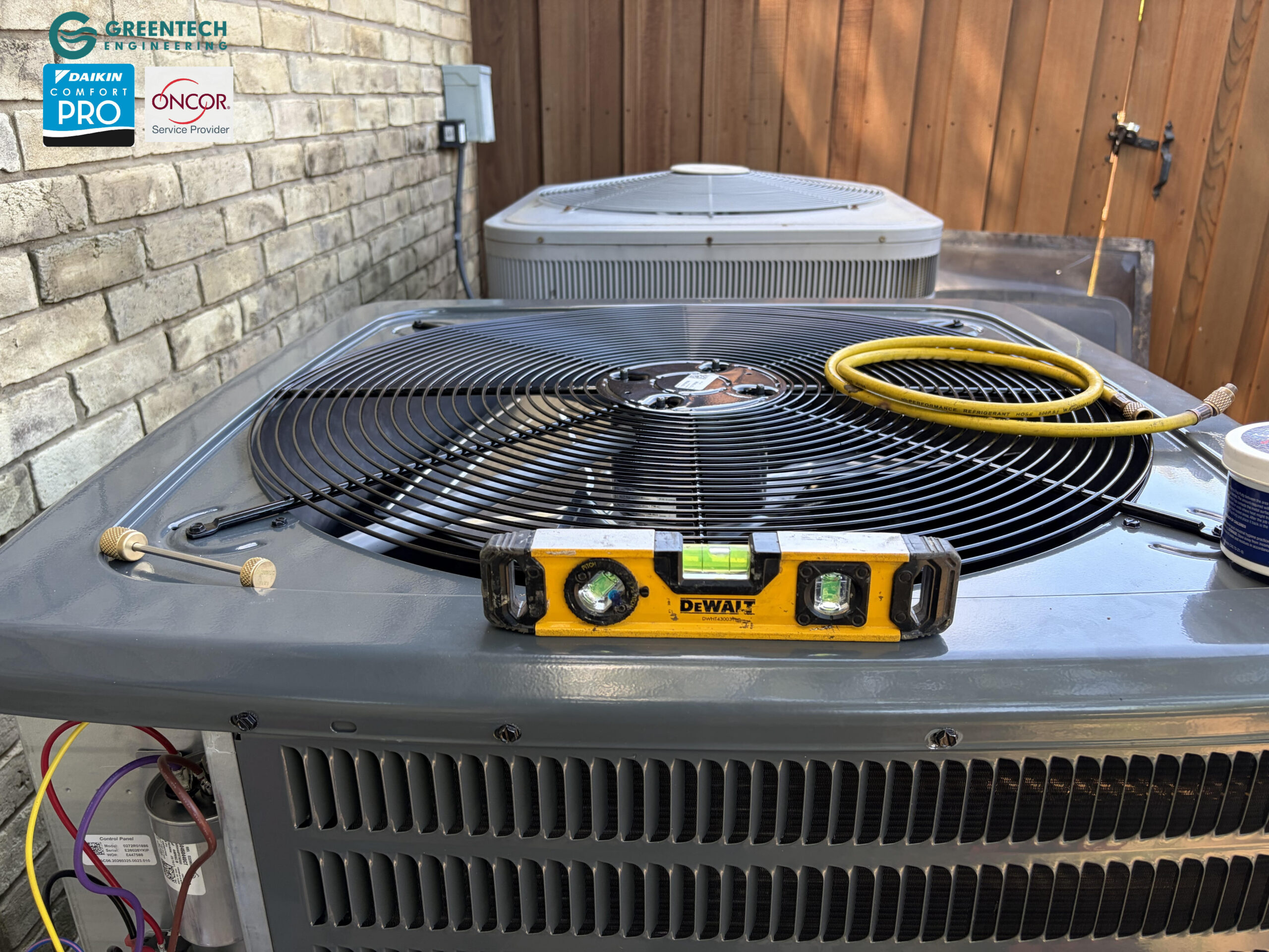 A yellow DeWalt spirit level sitting on top of a newly installed Goodman AC condenser fan guard, verifying the unit is perfectly leveled.