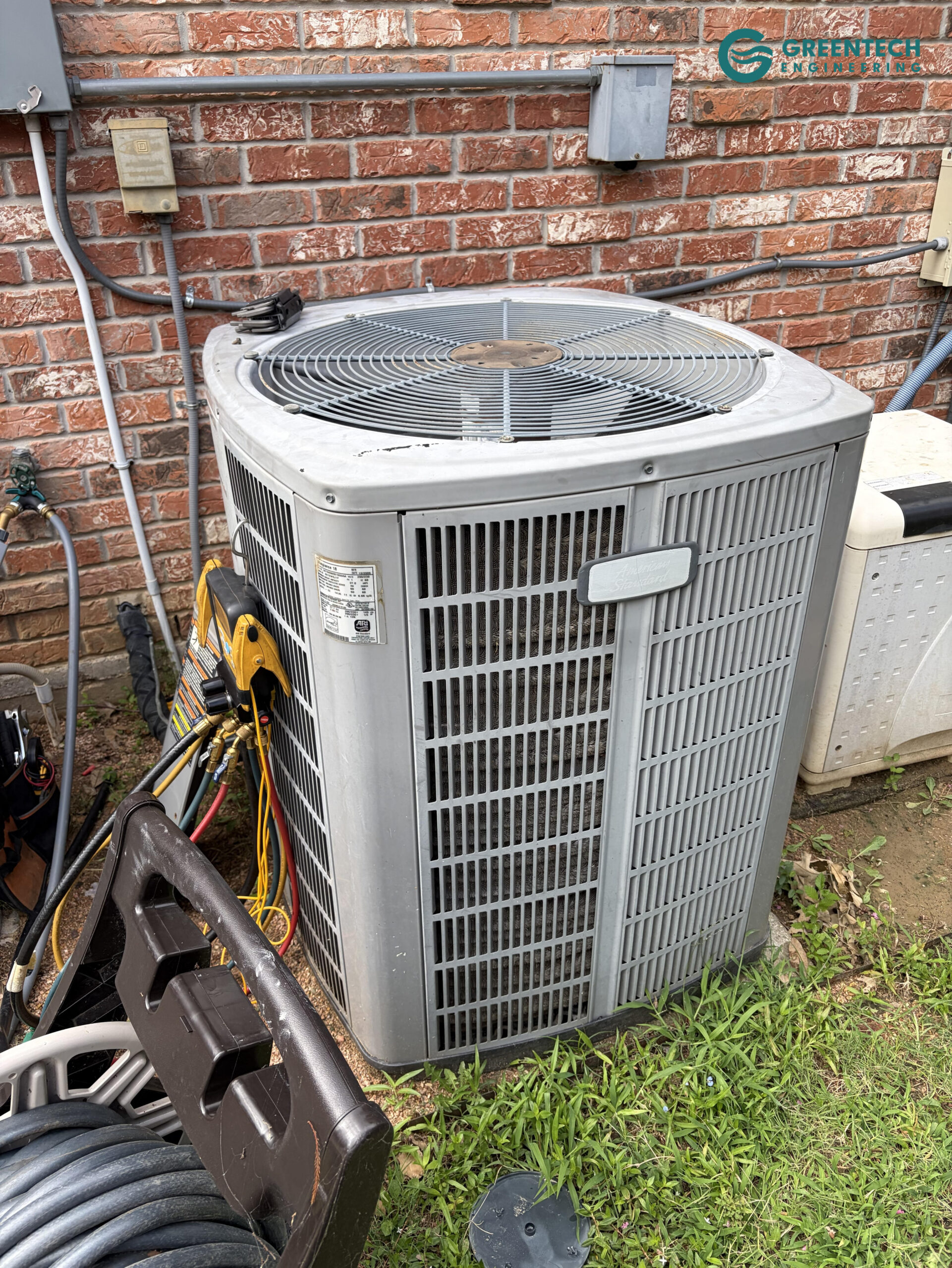 An aging, low-efficiency American Standard air conditioning condenser sitting outside a residential home in Dallas, Texas.