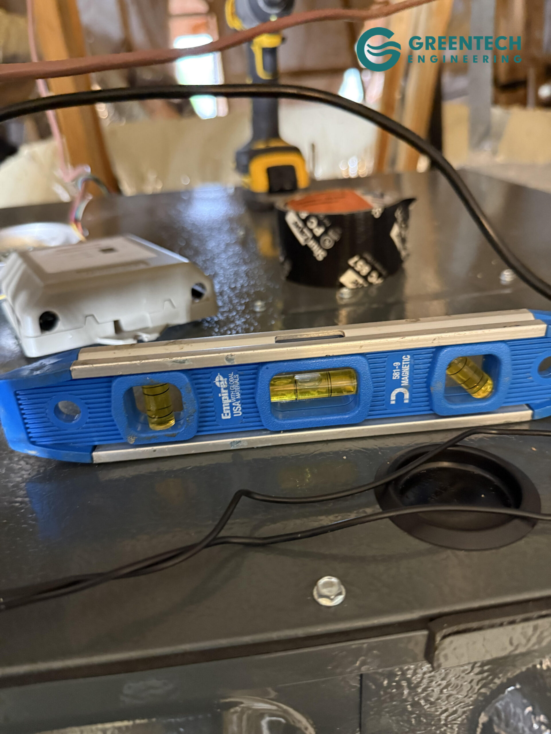 A blue Empire magnetic level resting on top of a newly installed metal indoor HVAC cabinet to ensure perfect horizontal alignment.