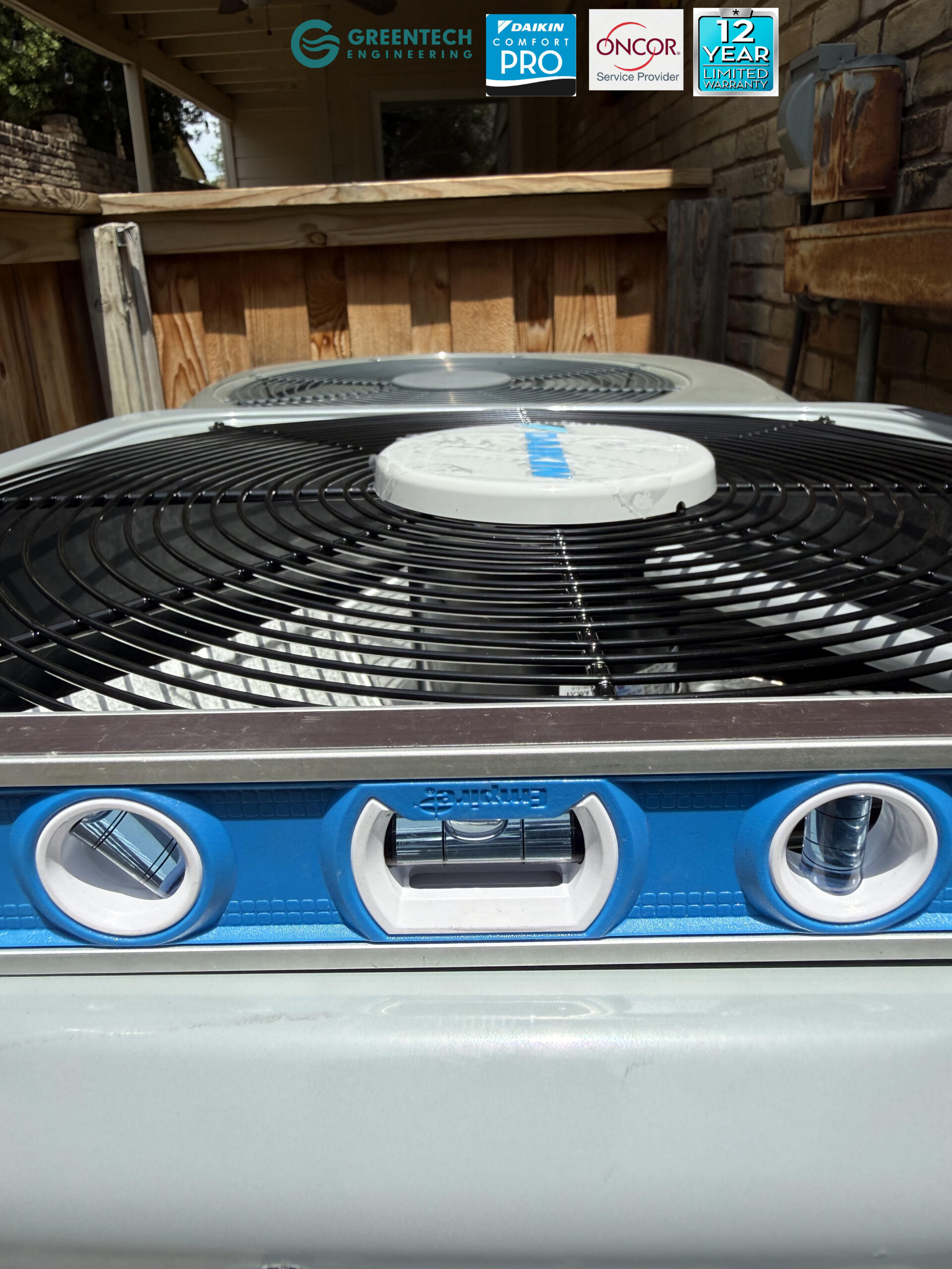 A blue Empire magnetic level resting perfectly flat on the fan grate of a newly installed Daikin air conditioning condenser.