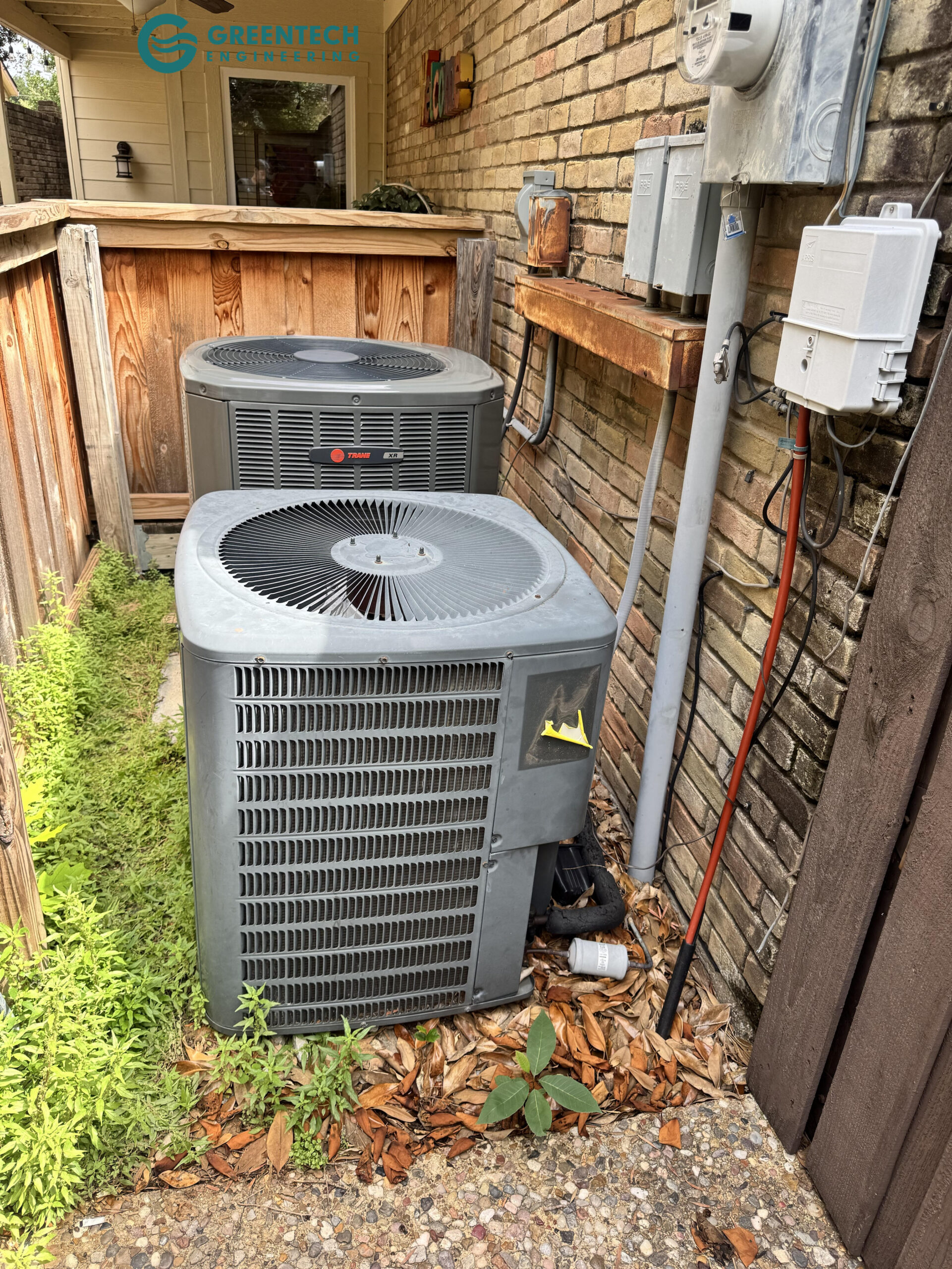 An old, inefficient Trane air conditioning condenser sitting beside a brick house in Dallas, Texas.