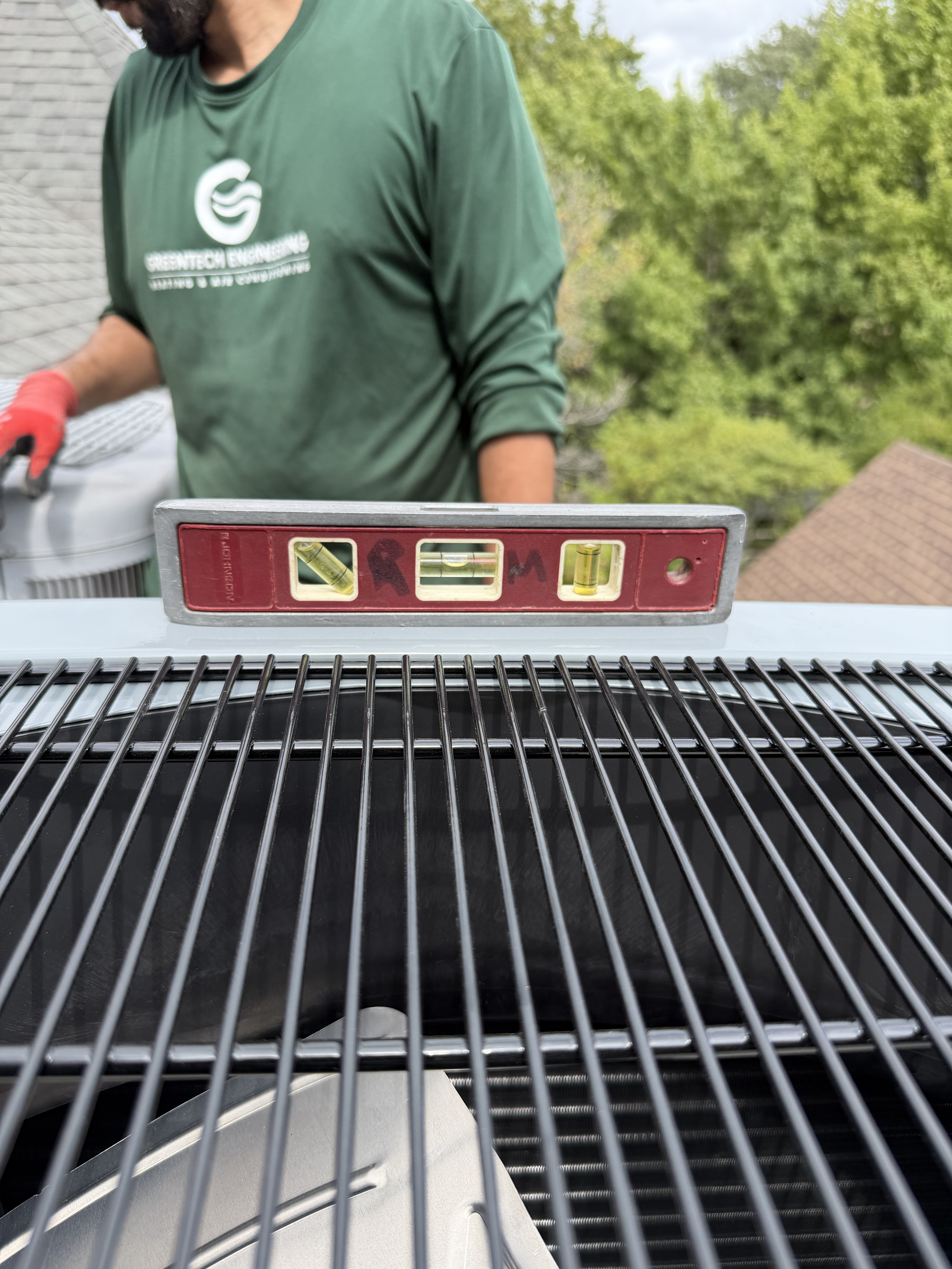 Technician checking the position of a residential rooftop HVAC condenser in Highland Park
