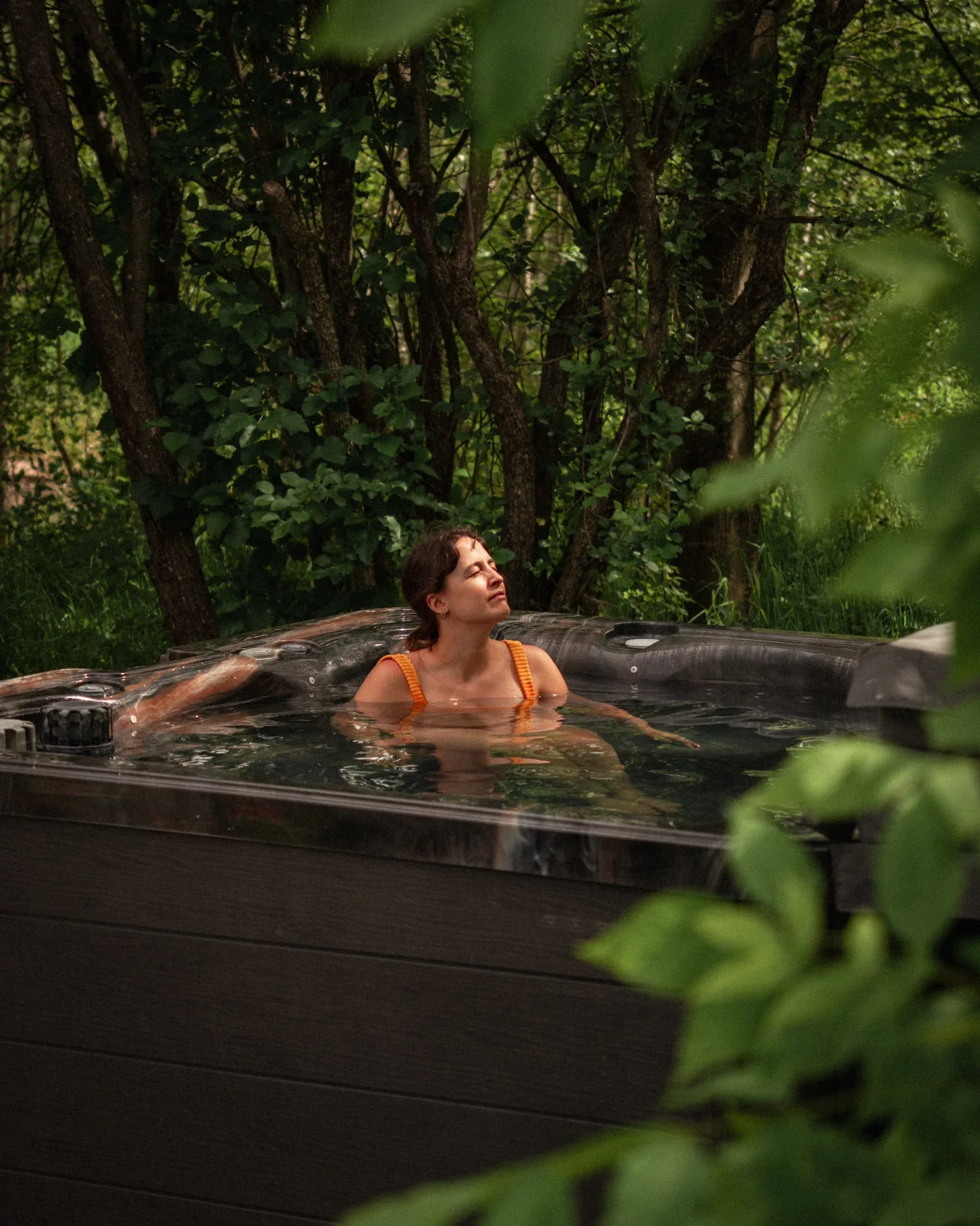 Femme se détendant dans un spa extérieur entouré de forêt dans les Cantons-de-l'Est
