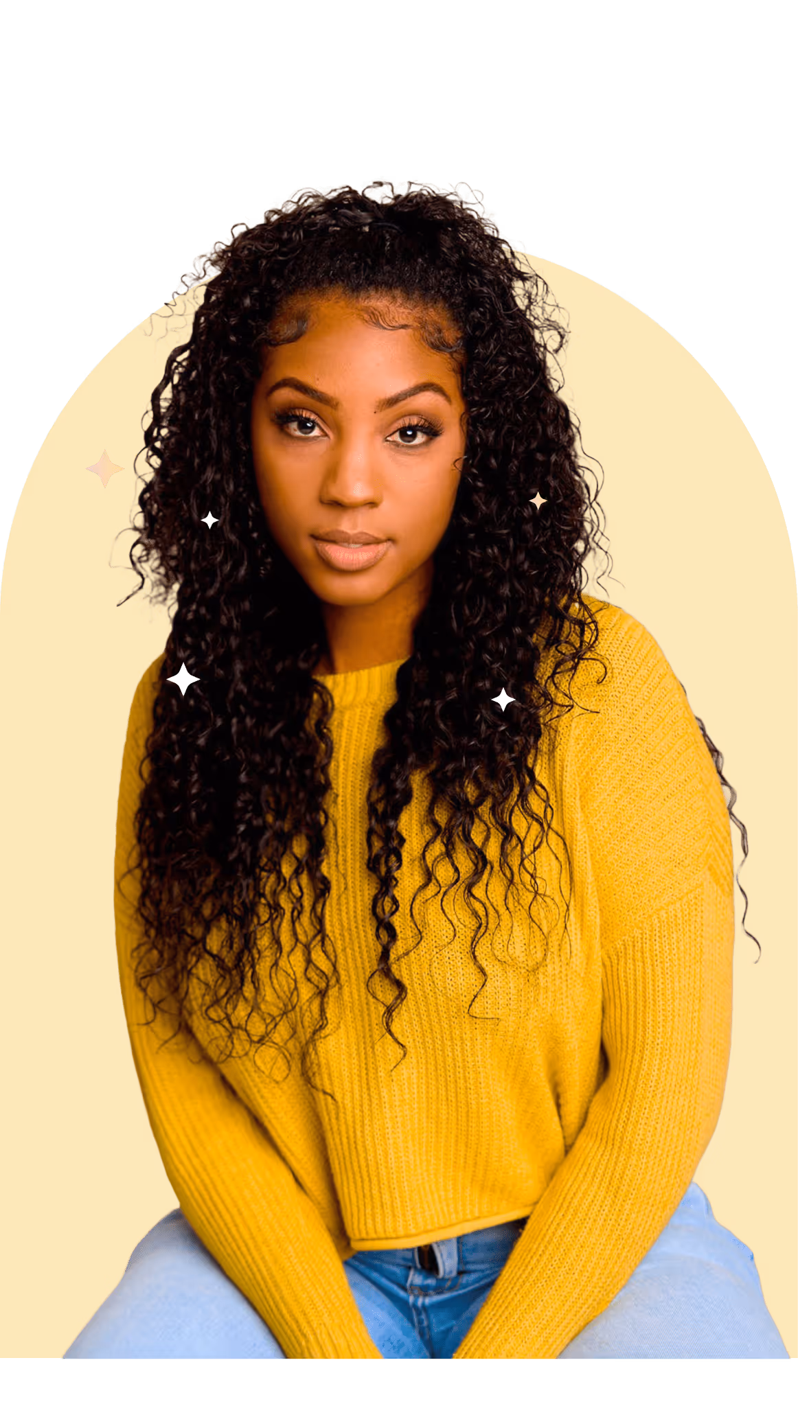 Headshot of a young woman with long, dark curly hair, wearing a vibrant yellow knitted sweater and light-wash jeans, looking directly at the camera.