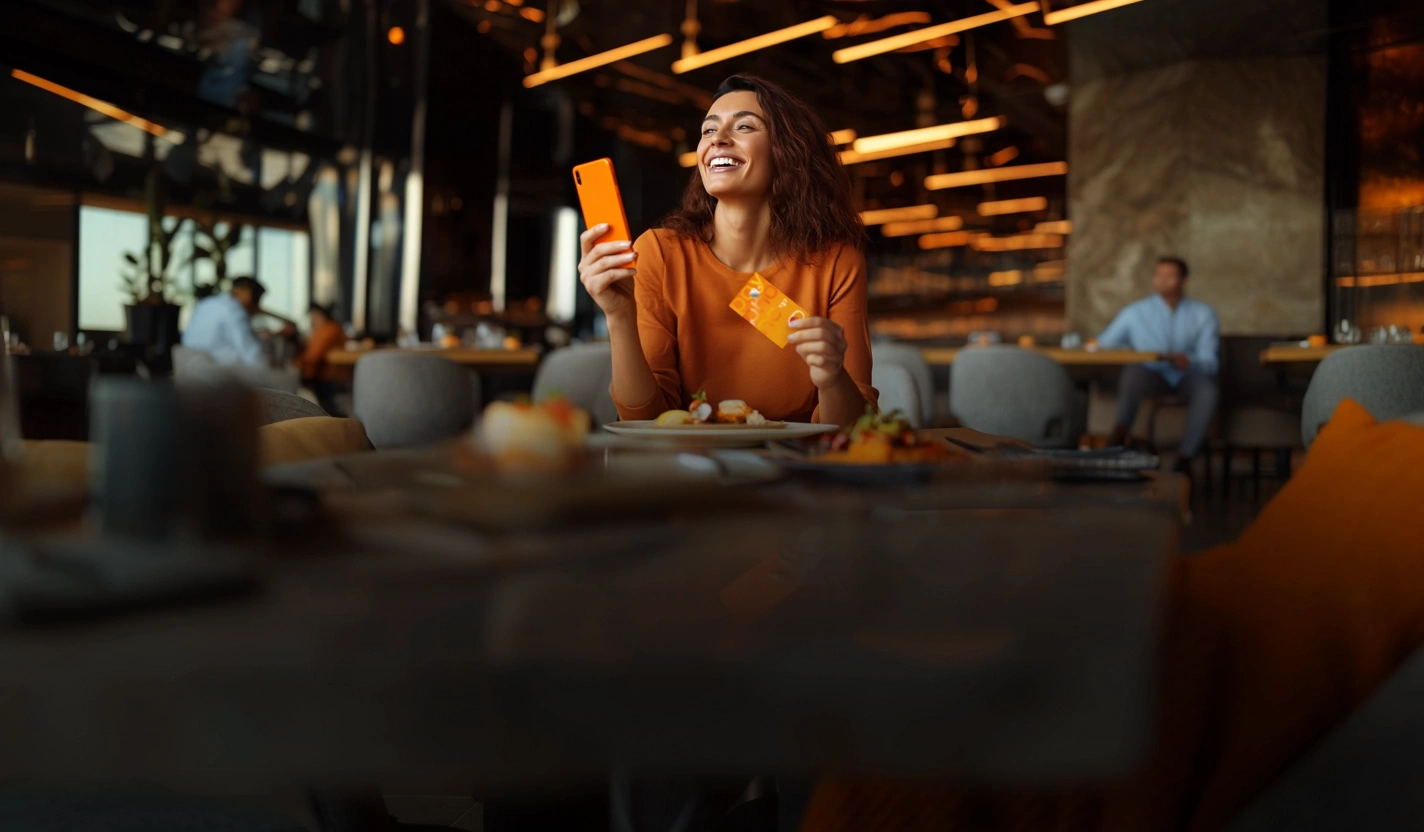 Mujer utiliza su Mastercard Payphone en un restaurante donde hay promociones de la tarjeta.
