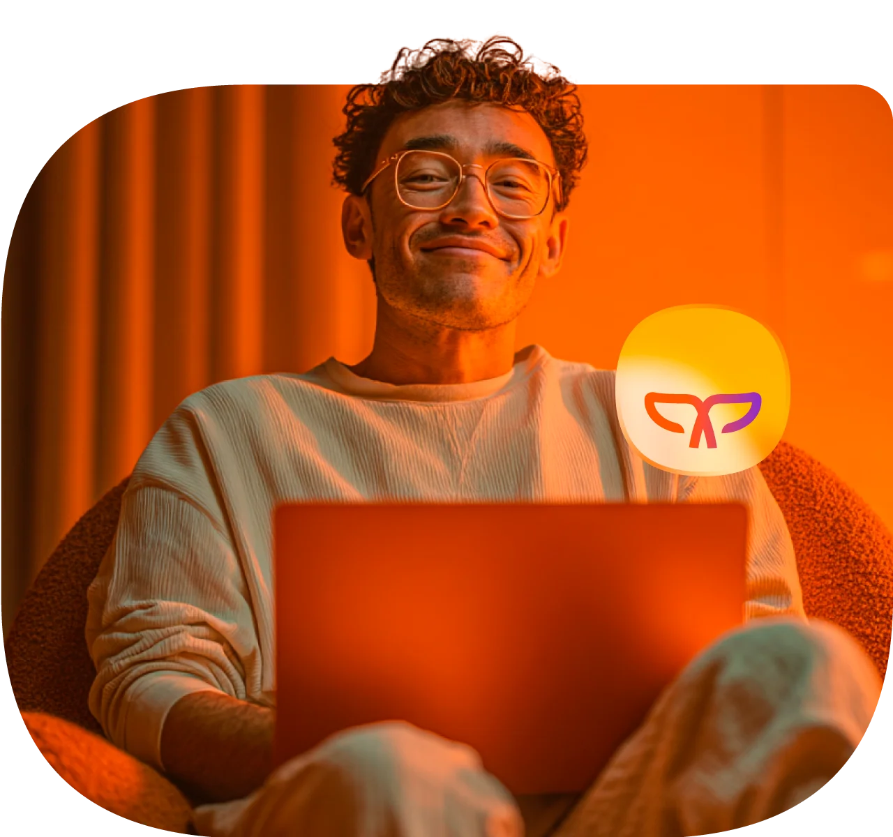Hombre sonrie a la cárama mientras se encuentra con su laptop.