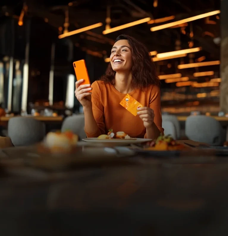 Mujer utiliza su Mastercard Payphone en un restaurante donde hay promociones de la tarjeta.