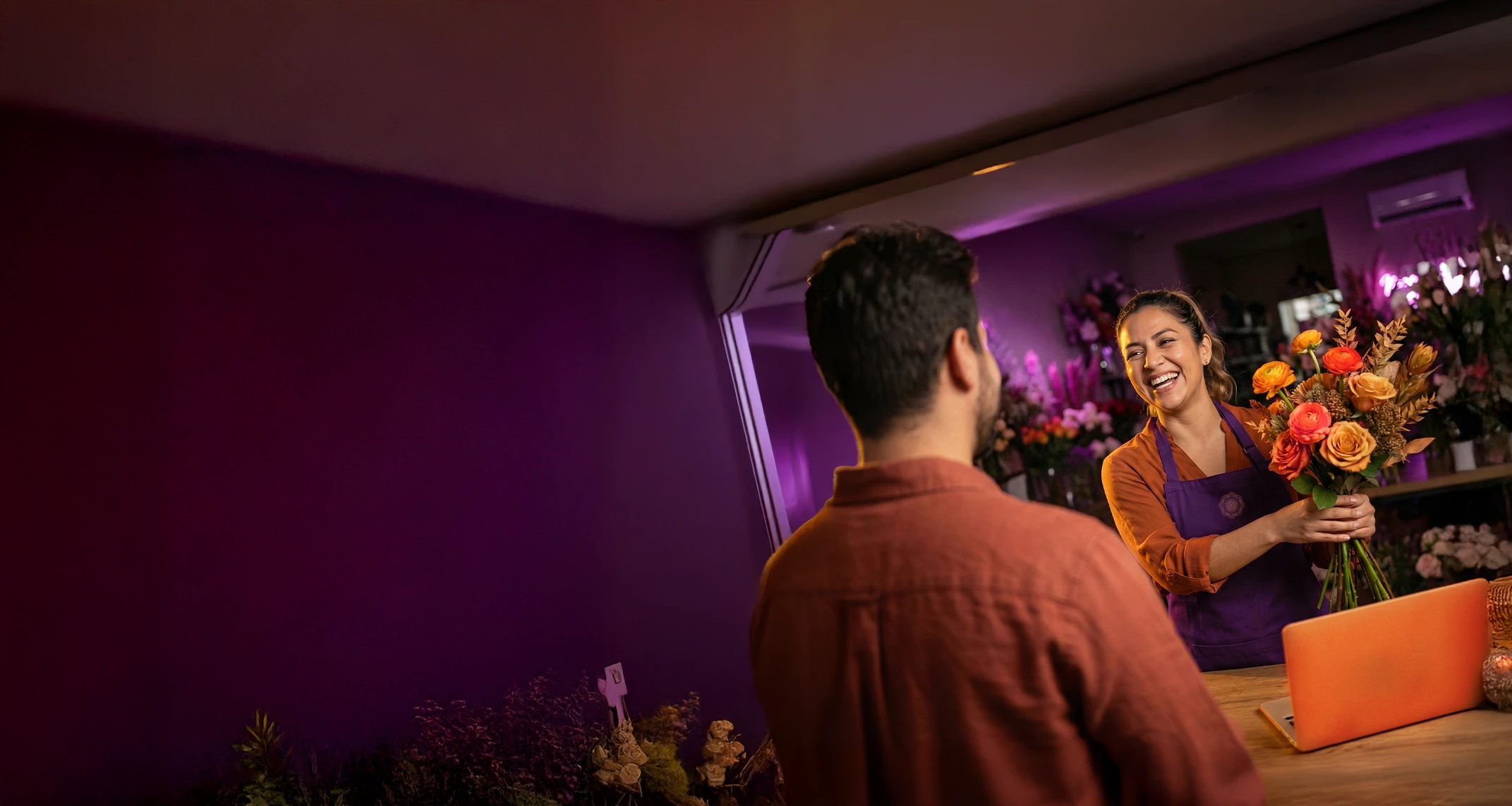 Emprendedora recibiendo flores de un hombre en el mostrador de su negocio.