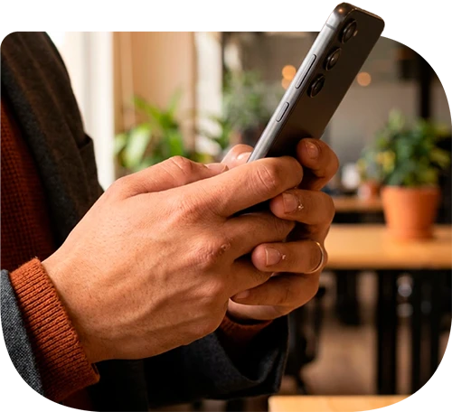 Manos usando un celular para recibir un pago digital.