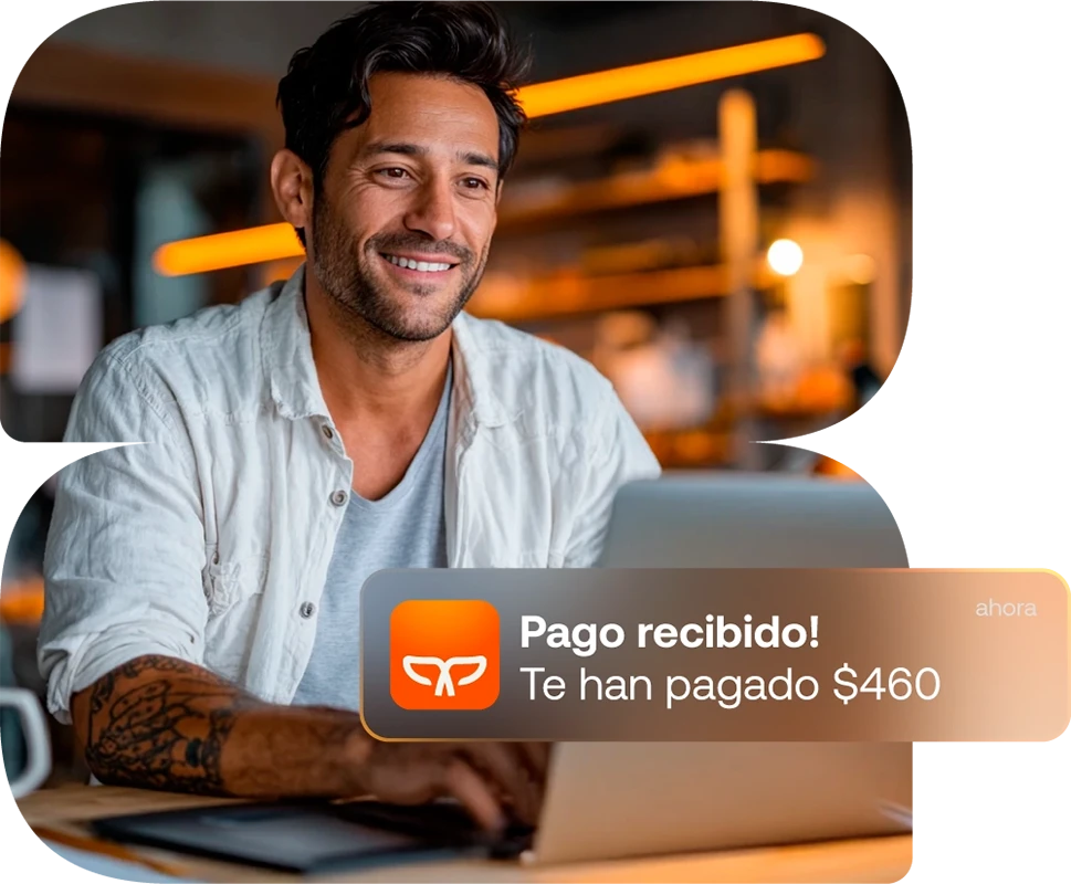 Hombre sonriendo frente a su laptop al recibir una notificación de pago.