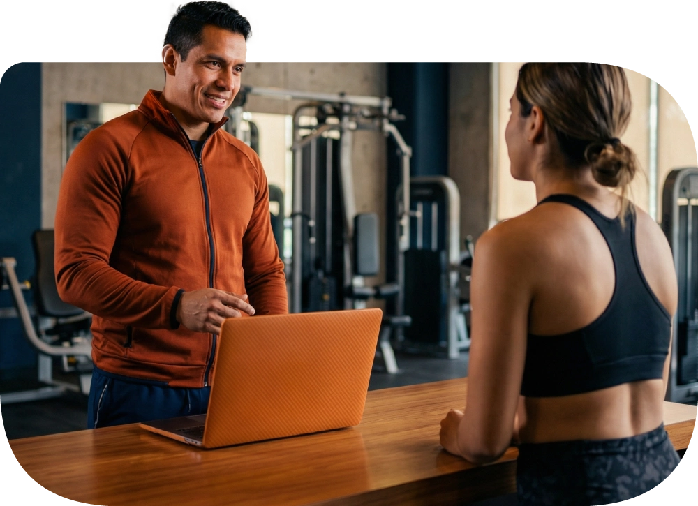 Recepcionista de gimnasio cobrando un servicio a una clienta en el mostrador.