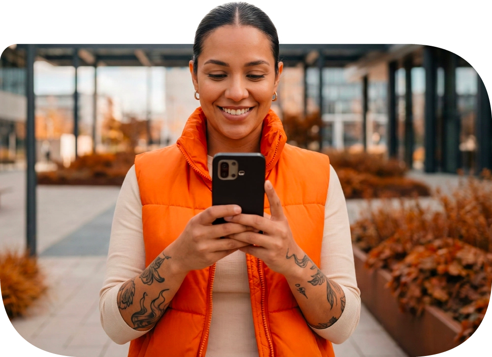 Compradora sonriendo al hacer un pago online en su celular.