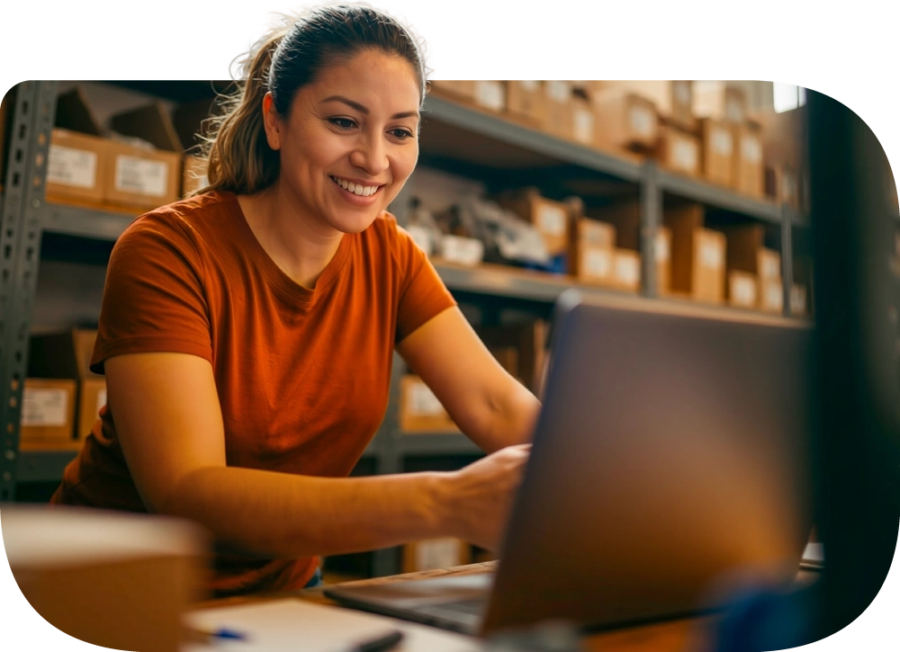 Persona gestionando cobros desde su laptop en la bodega de su tienda.