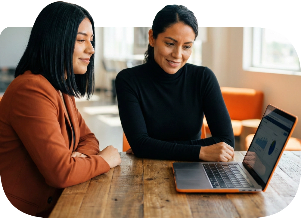 Socias de un comercio revisando información de ventas en una laptop.