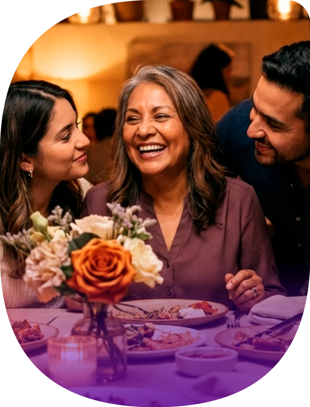 Familia celebrando el Día de la Madre en una cena con flores sobre la mesa.
