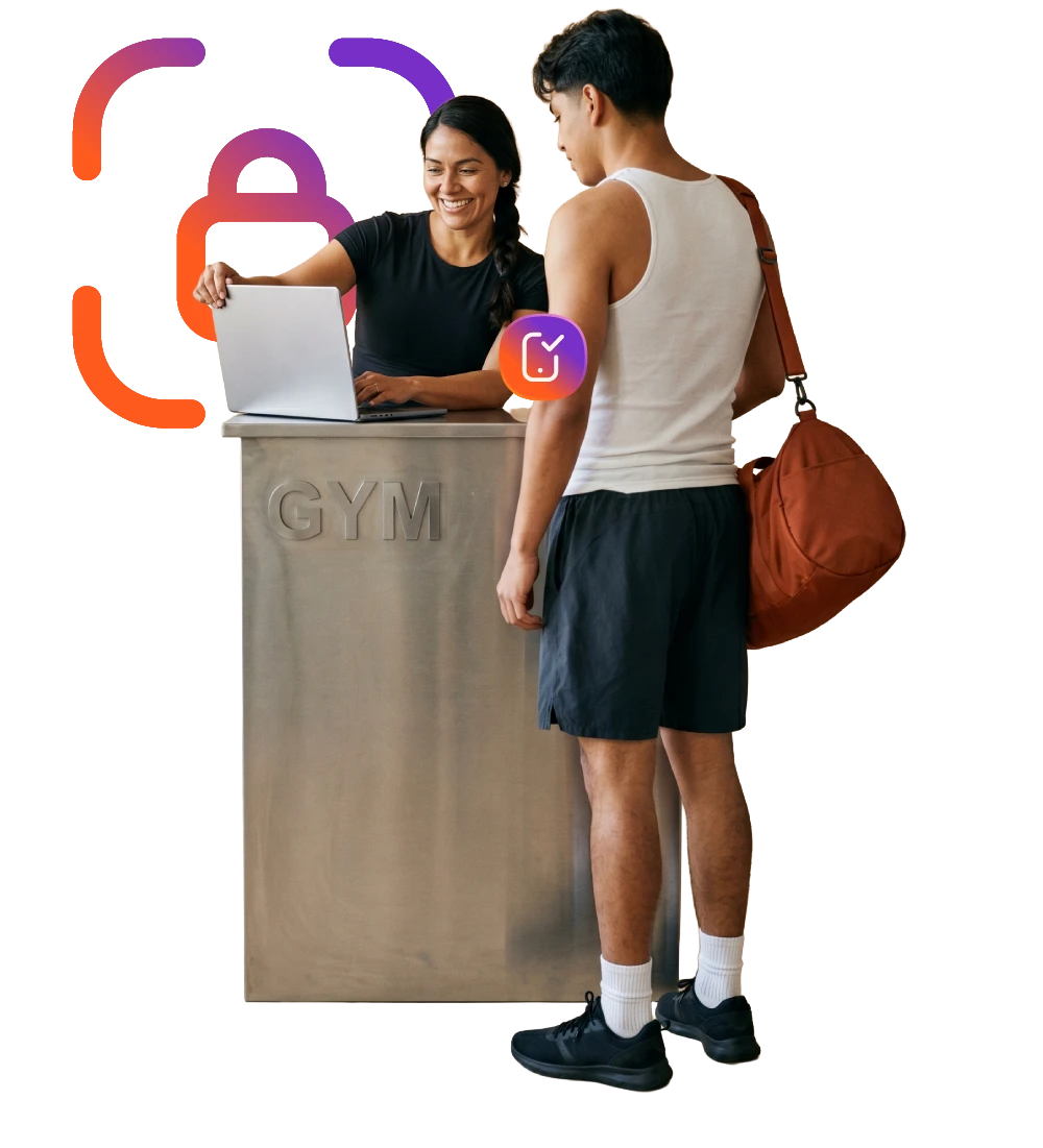 Recepcionista de gimnasio registrando a un cliente desde su laptop. 