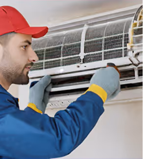 Technician servicing an air conditioning unit with tools and gloves for maintenance.