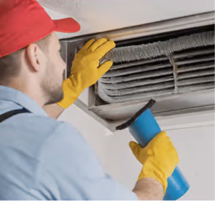 A technician in gloves cleans an air conditioning duct using a brush, promoting efficient HVAC maintenance.