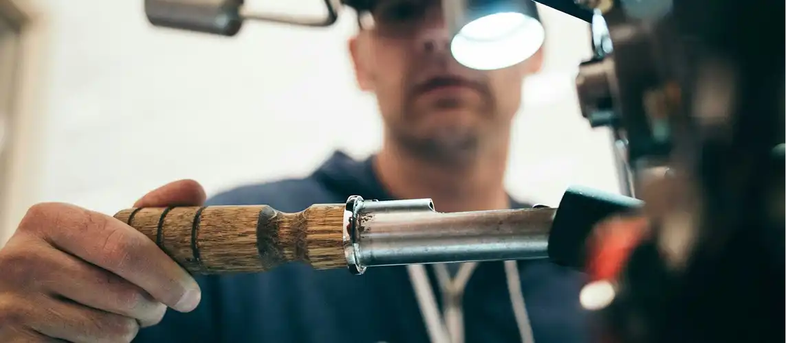 A technician inspects a tool under focused lighting in a workshop setting.
