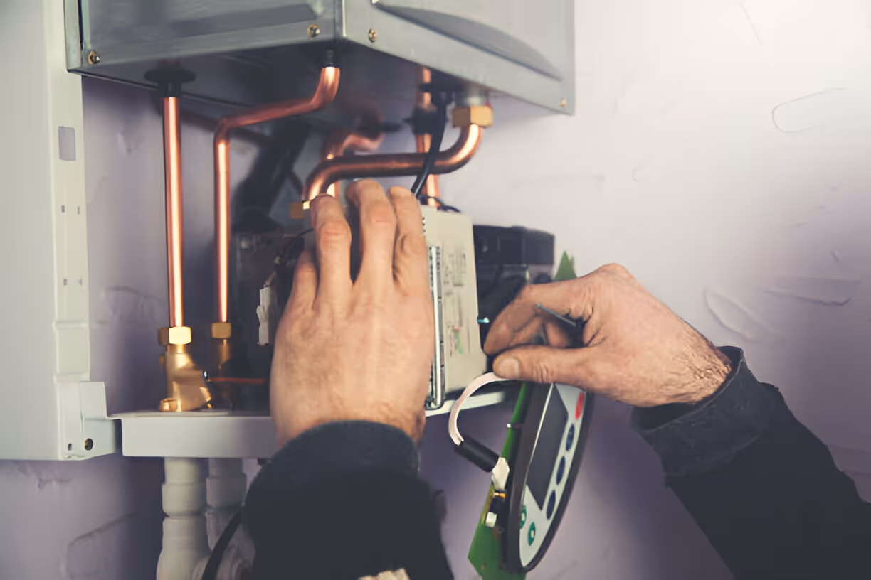 A technician repairs a heating system, focusing on the internal components and wiring connections.