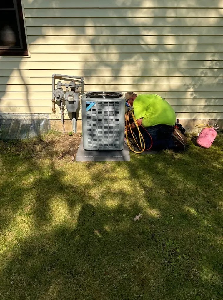 Technician performing an AC tune-up outdoors in a residential garden