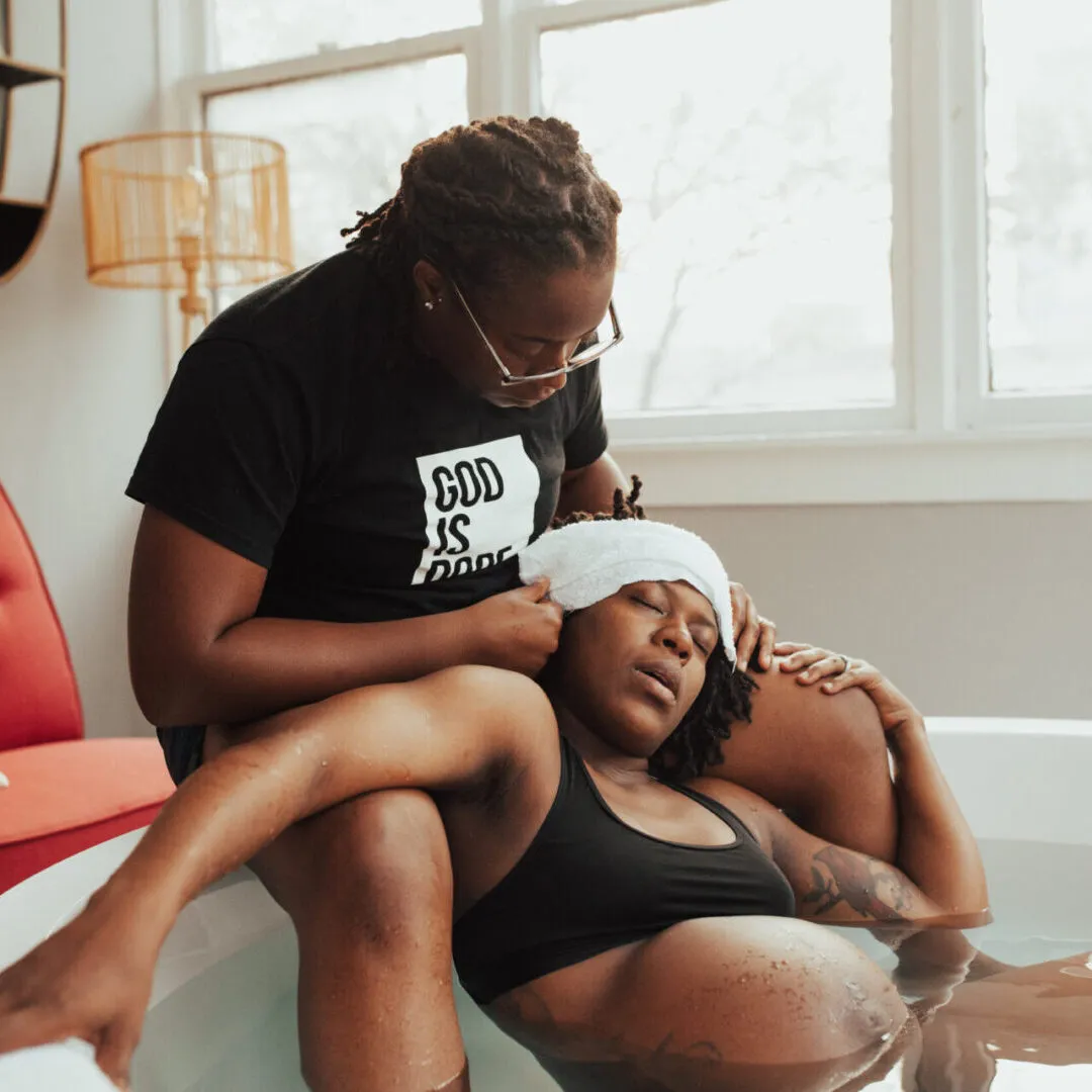 Doula assisting mother giving birth in water