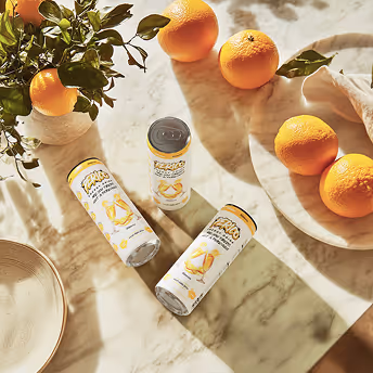 Perico Mimosa energy drinks styled with fresh oranges on a sunlit marble table, capturing a vibrant brunch and citrus lifestyle theme.
