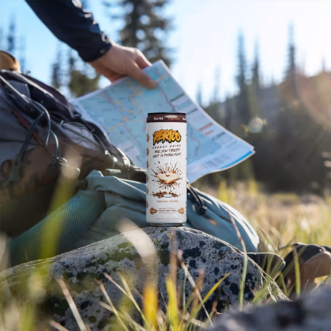 Espresso Martini Perico Energy Drink can on a hiking backpack in the forest, representing outdoor adventures and all-natural sustained energy for trail and travel. Featured on the Home and Product pages under the "Outdoors" tab.