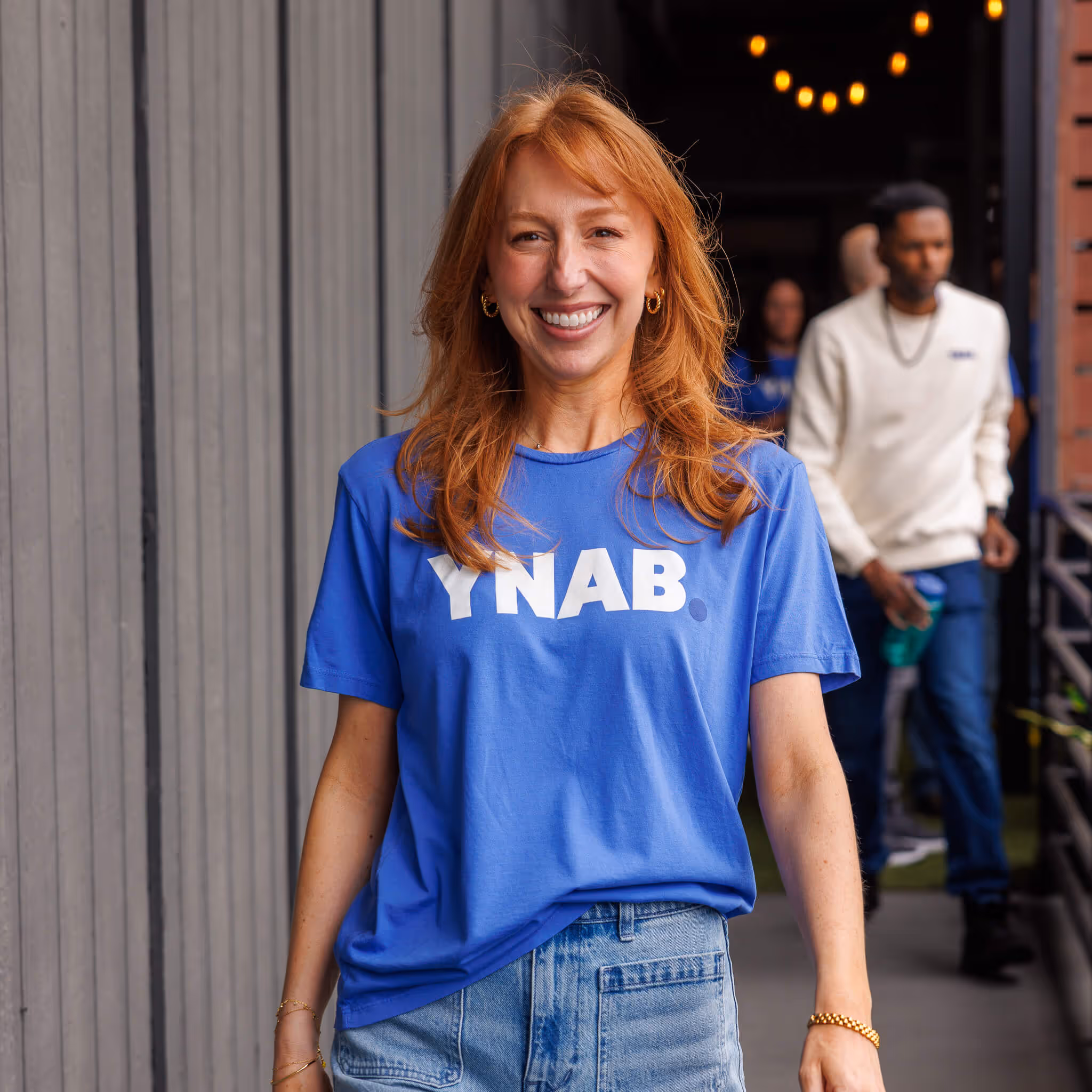 Person wearing a blue YNAB T-shirt smiling outdoors.