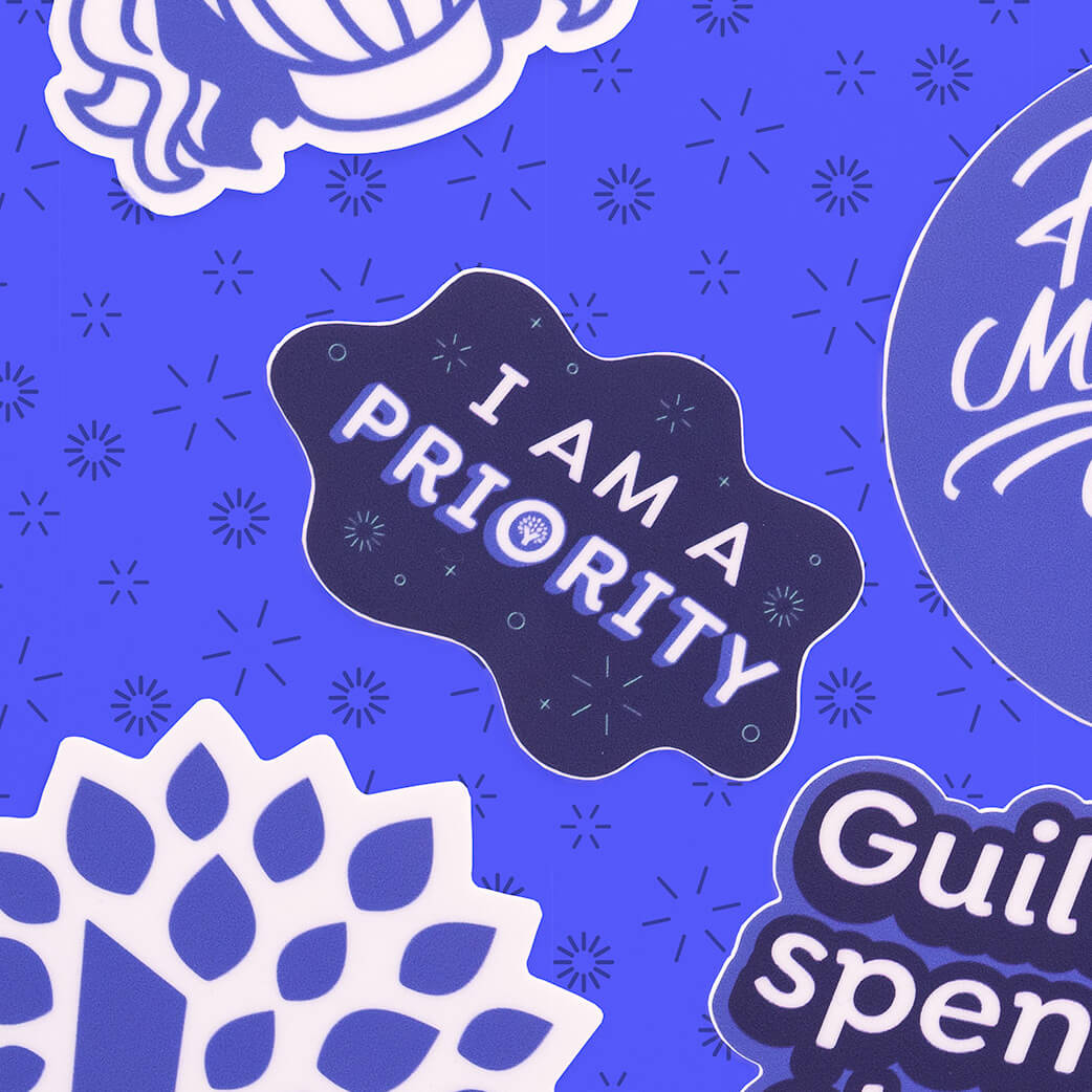 YNAB sticker reading “I am a priority” surrounded by other YNAB stickers on dark blue background.