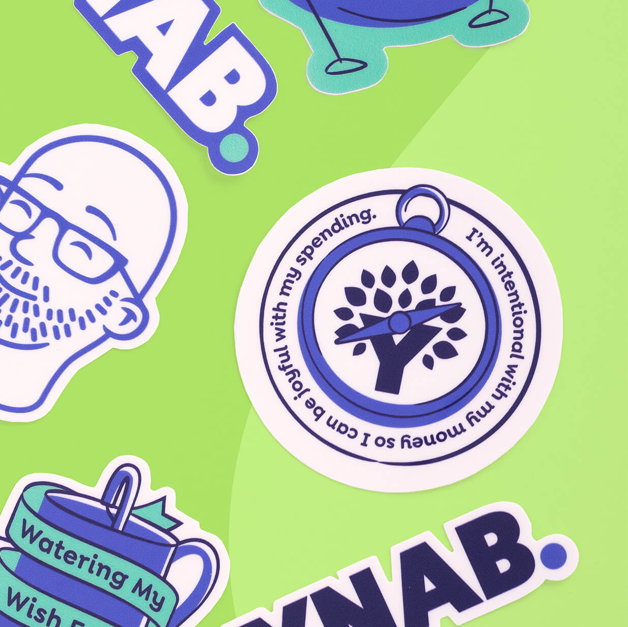 Circular YNAB sticker designed like a compass that reads “I’m intentional with my money so I can be joyful with my spending,” on a green background with other YNAB stickers.
