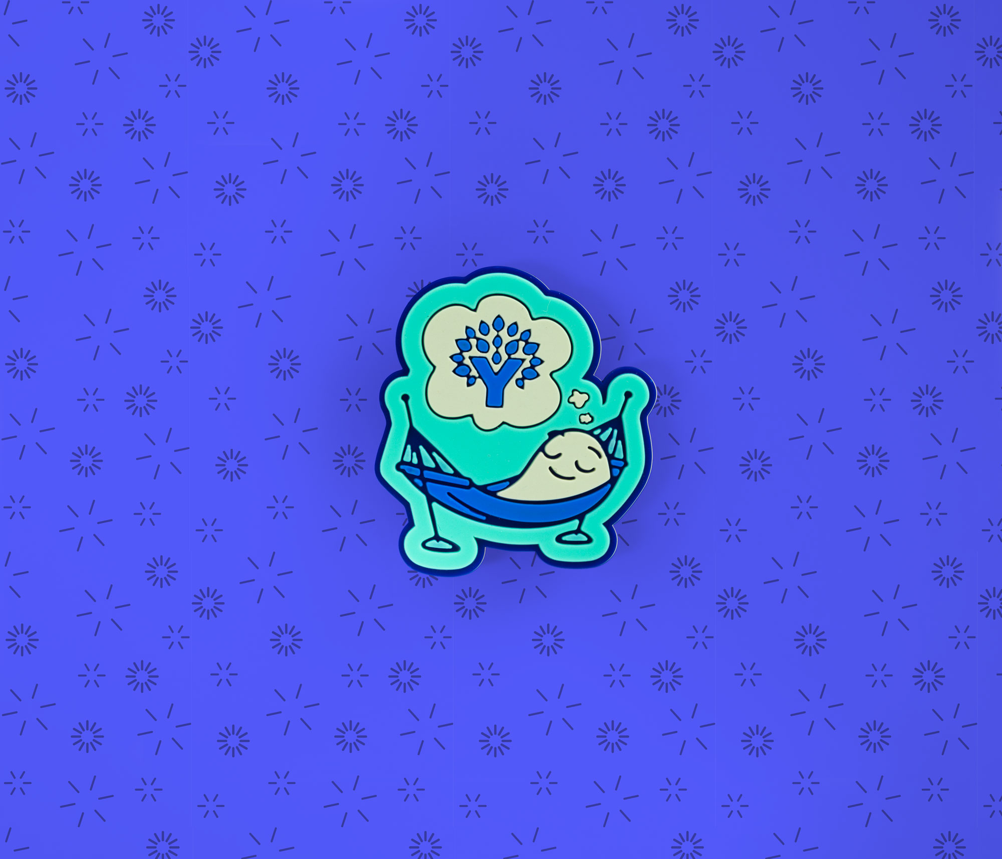 YNAB Croc charm shaped like a relaxed character in a hammock dreaming of the YNAB logo, displayed on a blue patterned background.