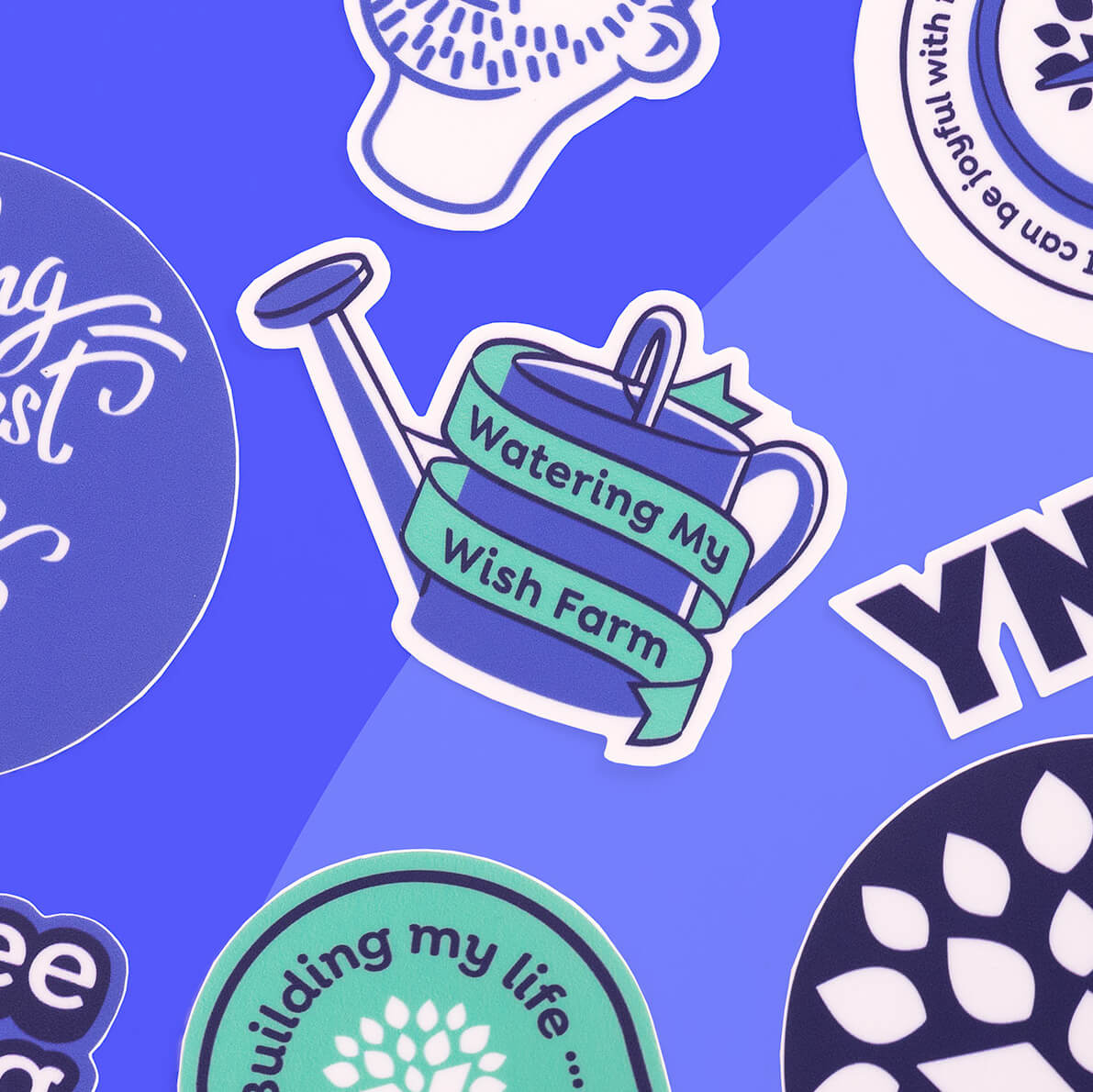 blurple-bg.jpg YNAB vinyl sticker featuring a blue watering can wrapped in a teal ribbon that reads “Watering My Wish Farm,” surrounded by other YNAB stickers on a blue background.