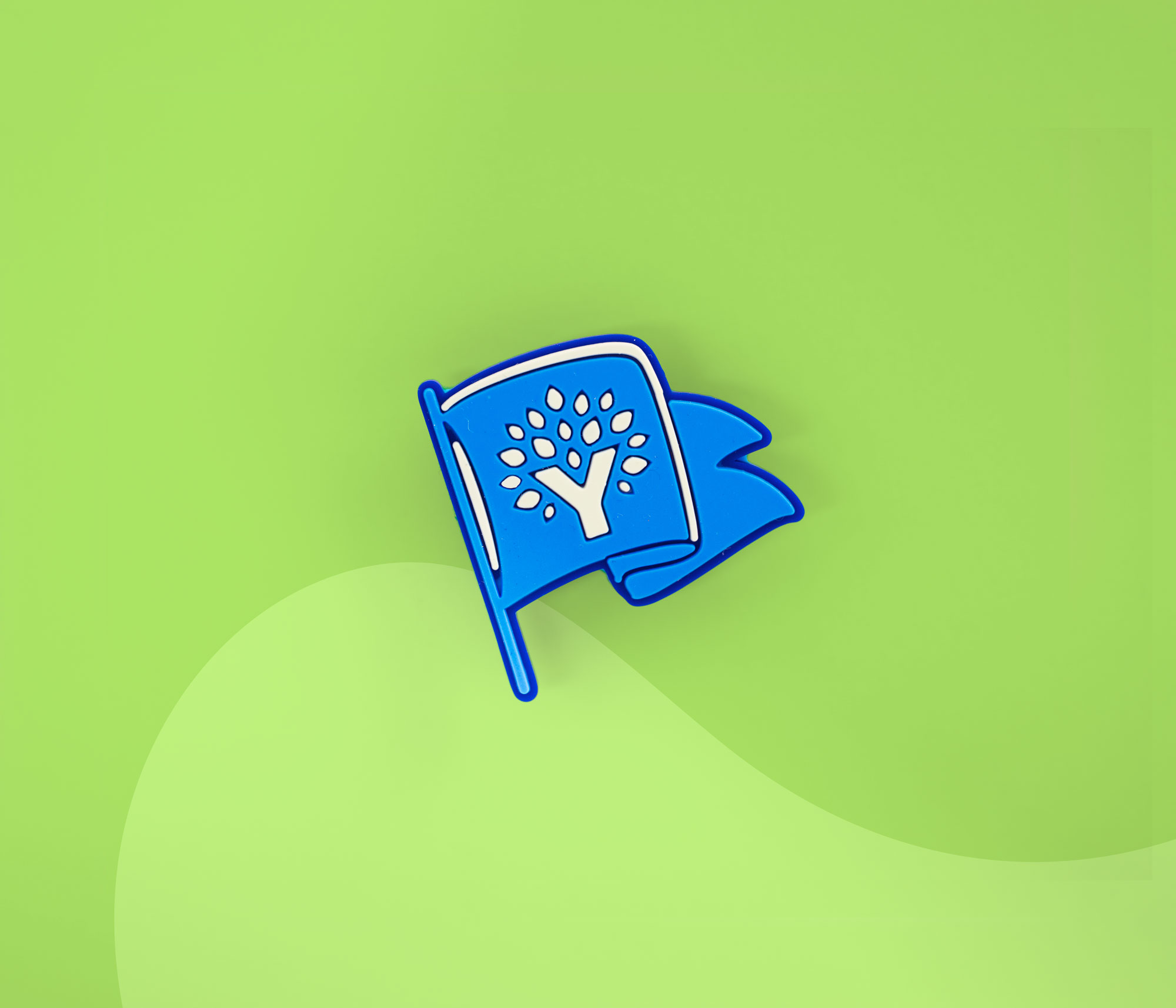 Blue YNAB flag-shaped Croc charm displayed on a green background.