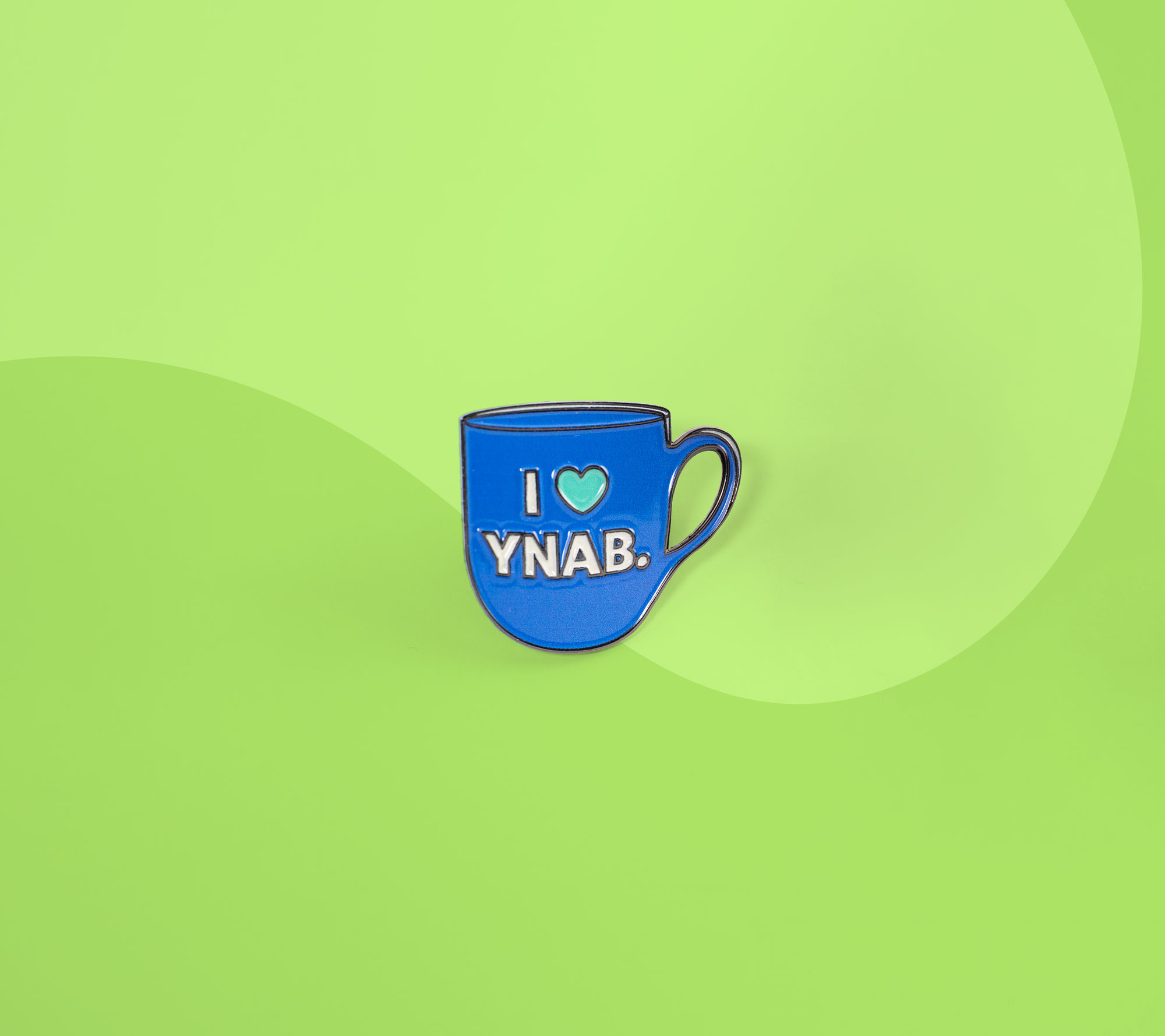 Blue enamel pin shaped like a coffee mug with the text "I love YNAB." displayed on a green background.