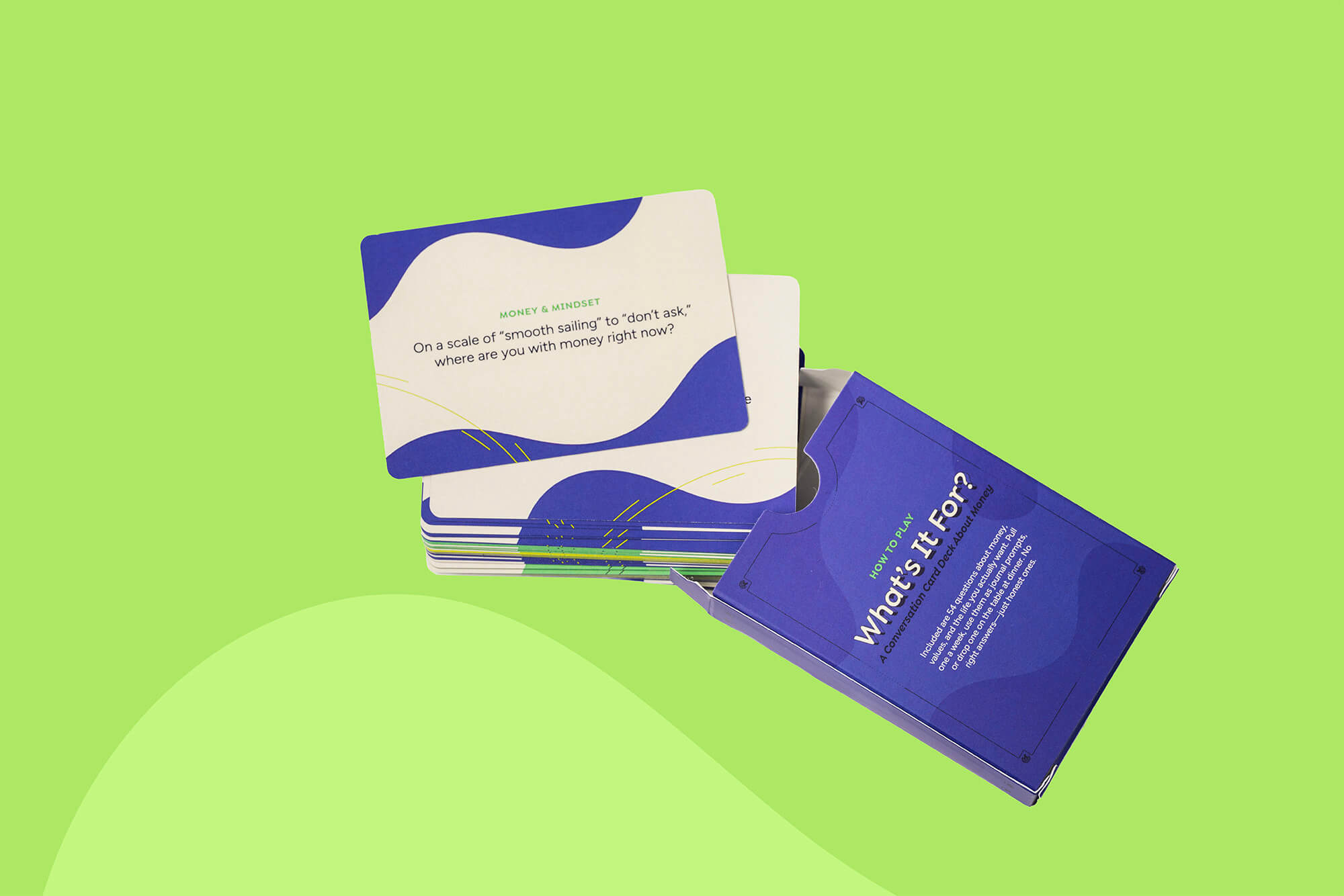 A boxed card game set with several cards fanned out beside the box on a bright green background. The visible box is blue with white text reading "What's It For?" and the cards are cream and blue with small green accents.