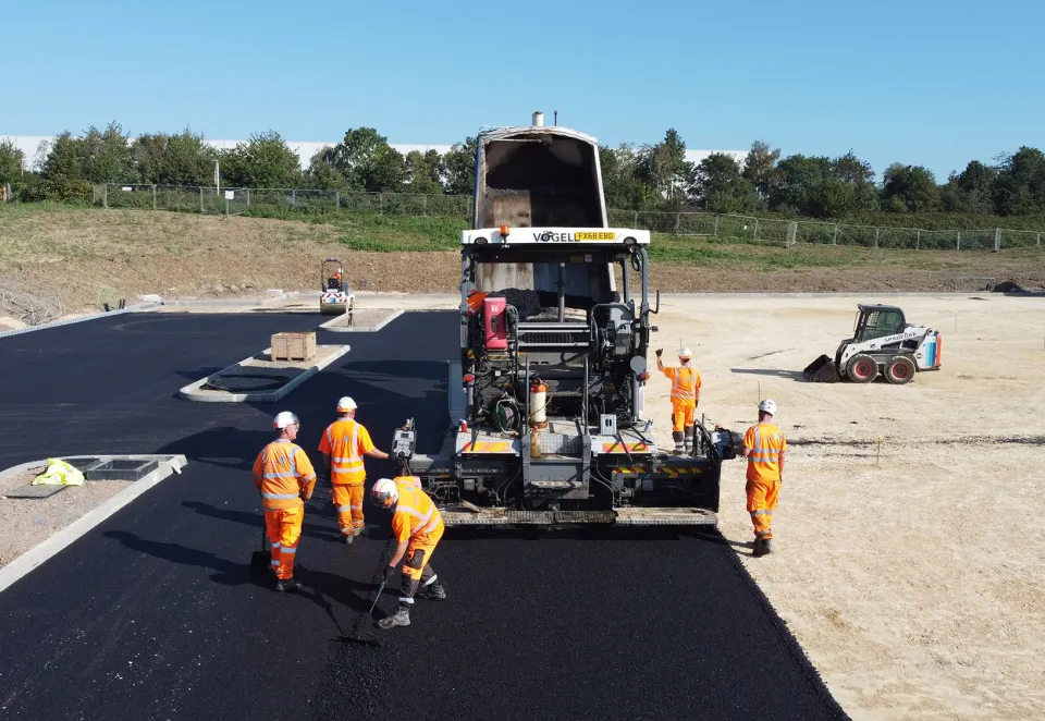 Crew laying fresh asphalt with VÖGELE paver on a commercial development site