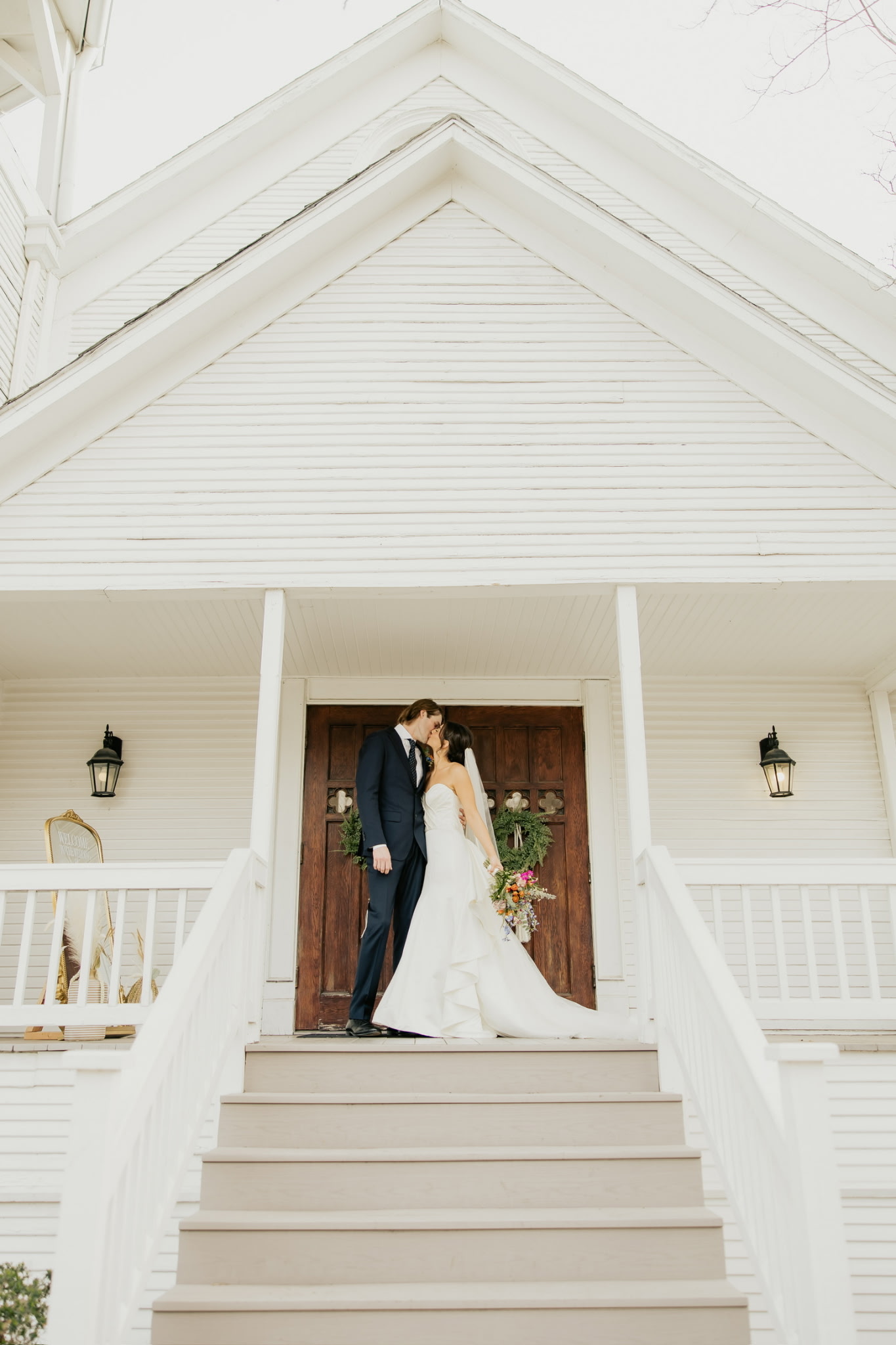 Newly married couple kissing in front of historic chapel