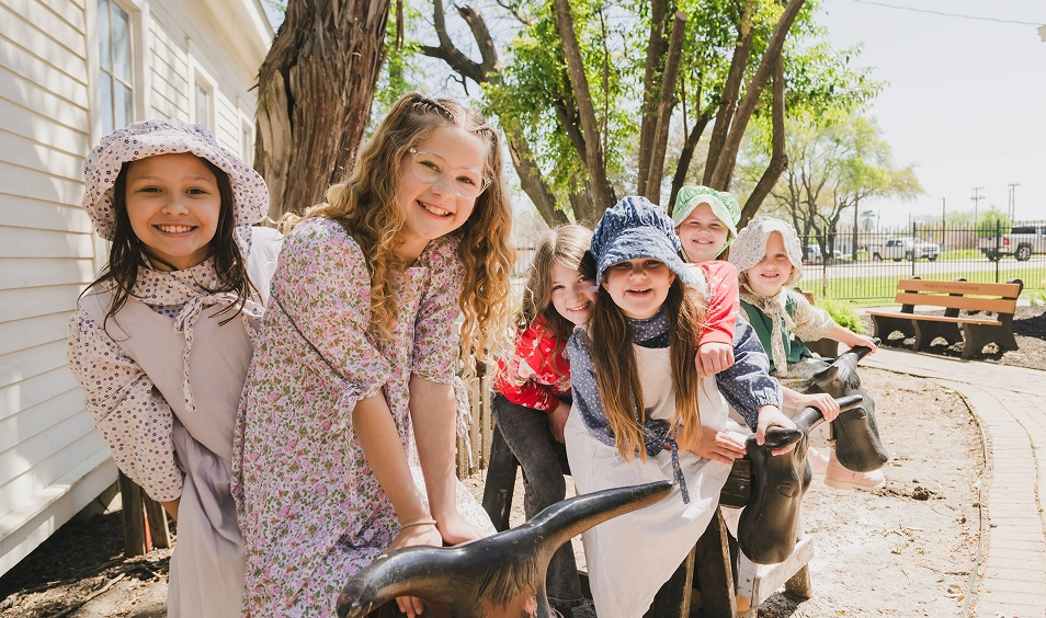 Kids dressed in period-piece clothing are smiling