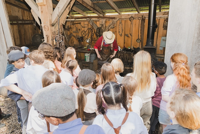 A blacksmith teaches a class how to work with metal