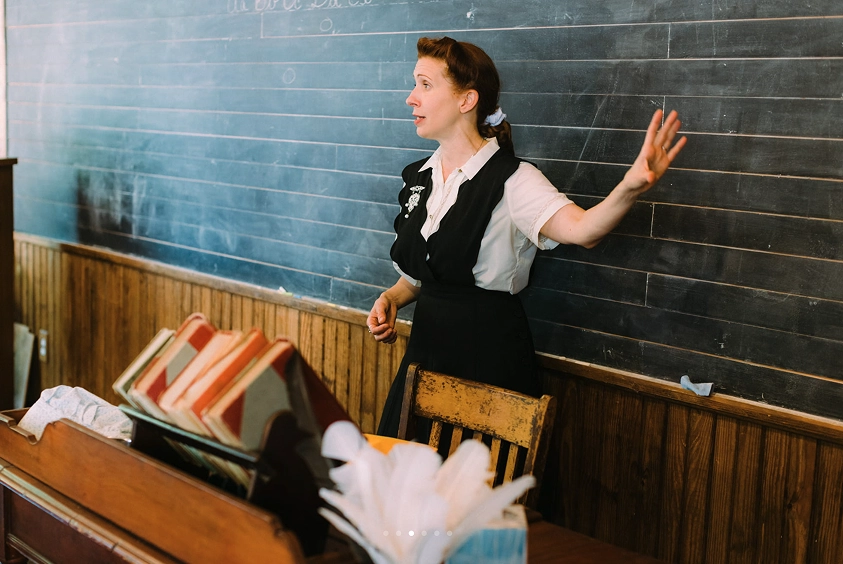 A teacher reenacts class from the 1800s inside the historic schoolhouse