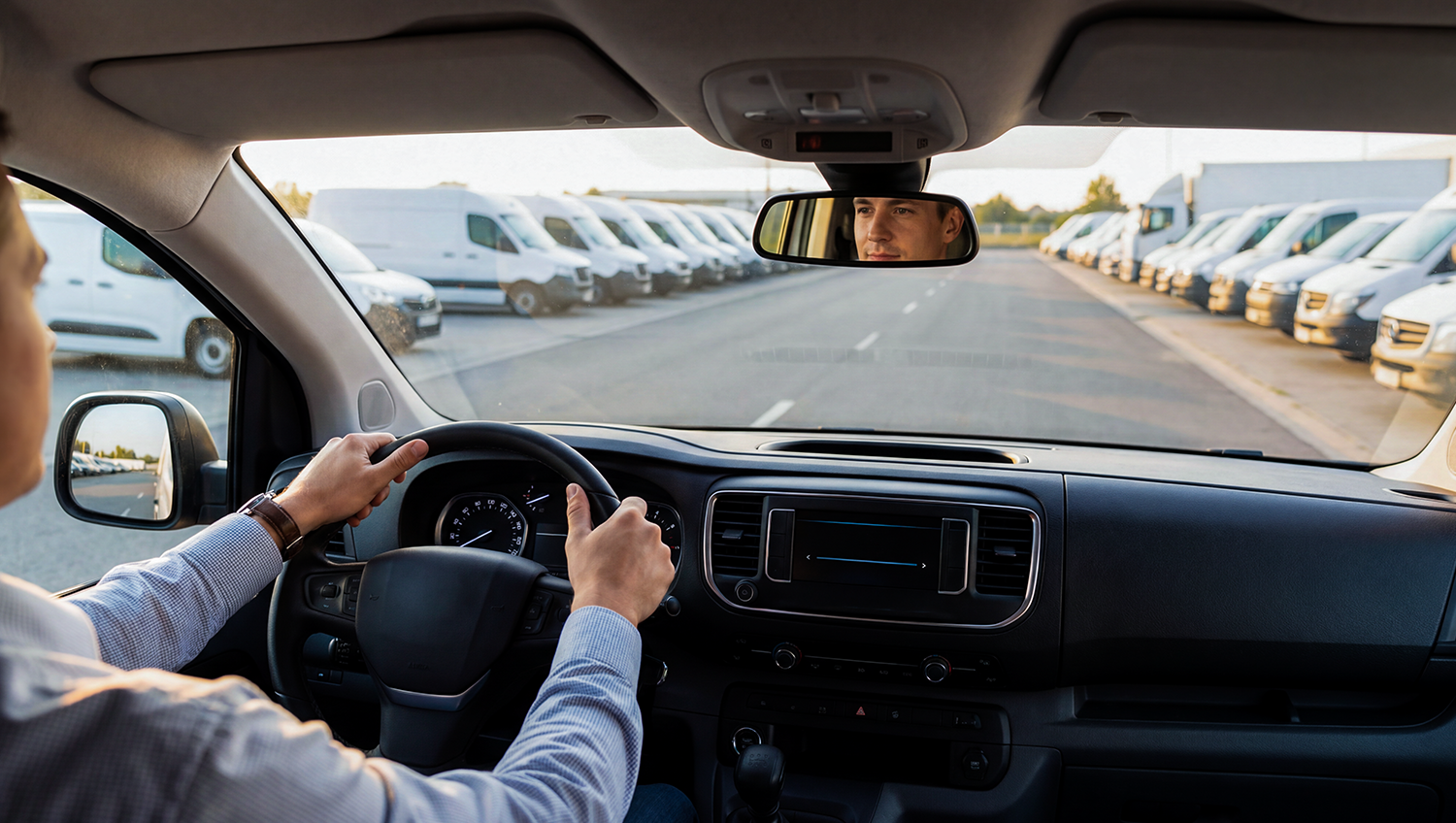 Driver in a vehicle looking at parked vans, illustrating how to choose the best GPS tracker for cars and fleet vehicles