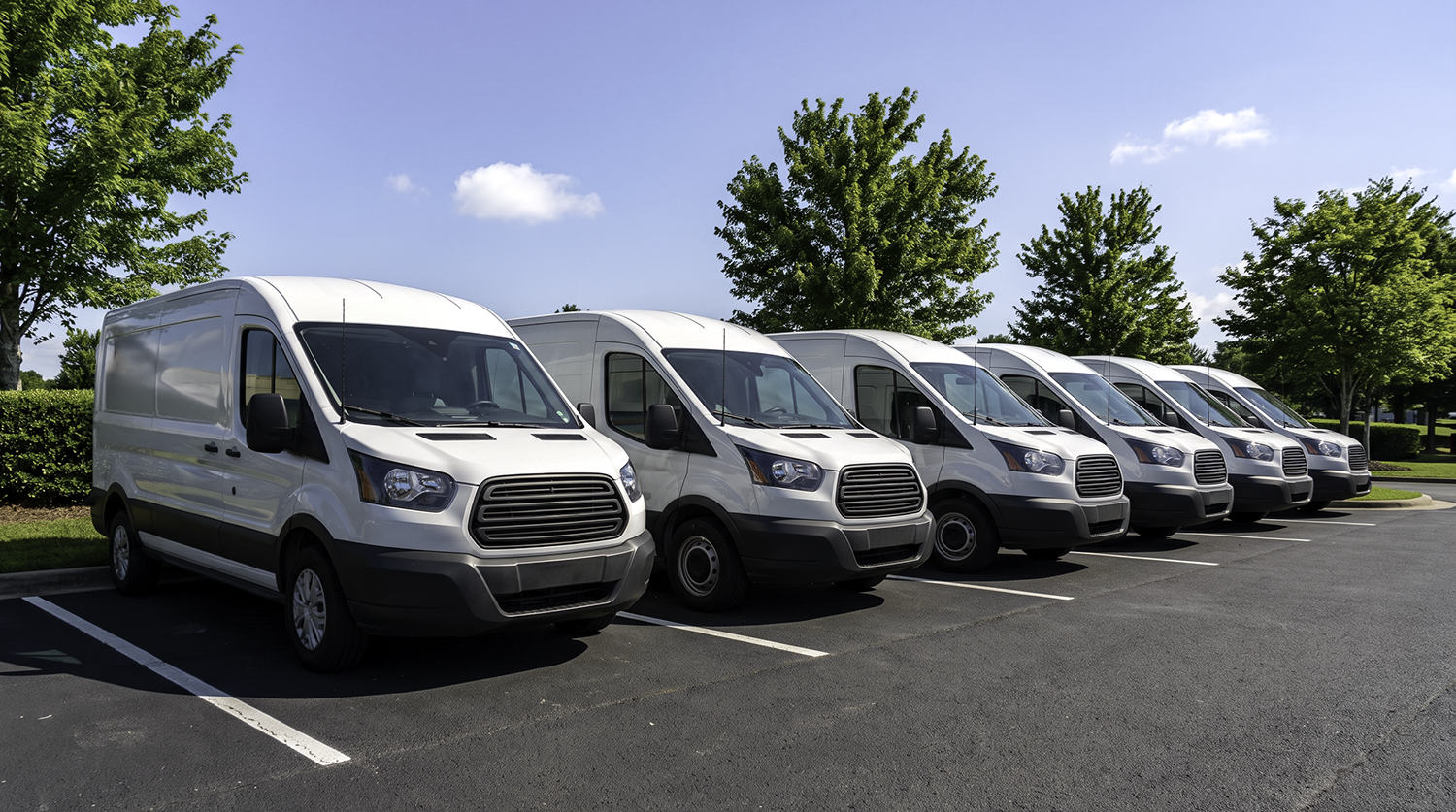Fleet of white service vans parked in a row, representing van tracking solutions for small and mid-size fleets