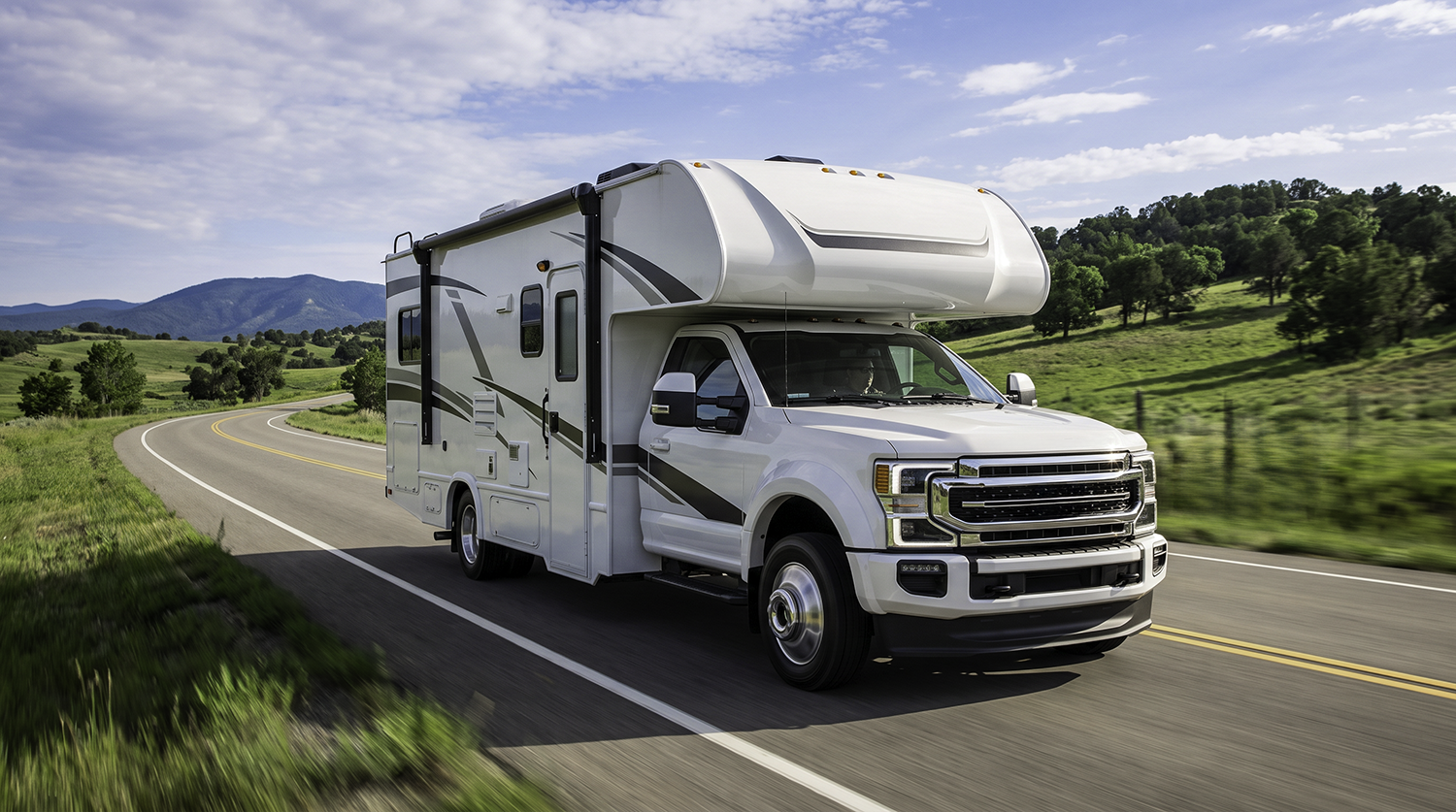 Class C motorhome driving a country highway, the RV type an RV GPS tracker plugs into