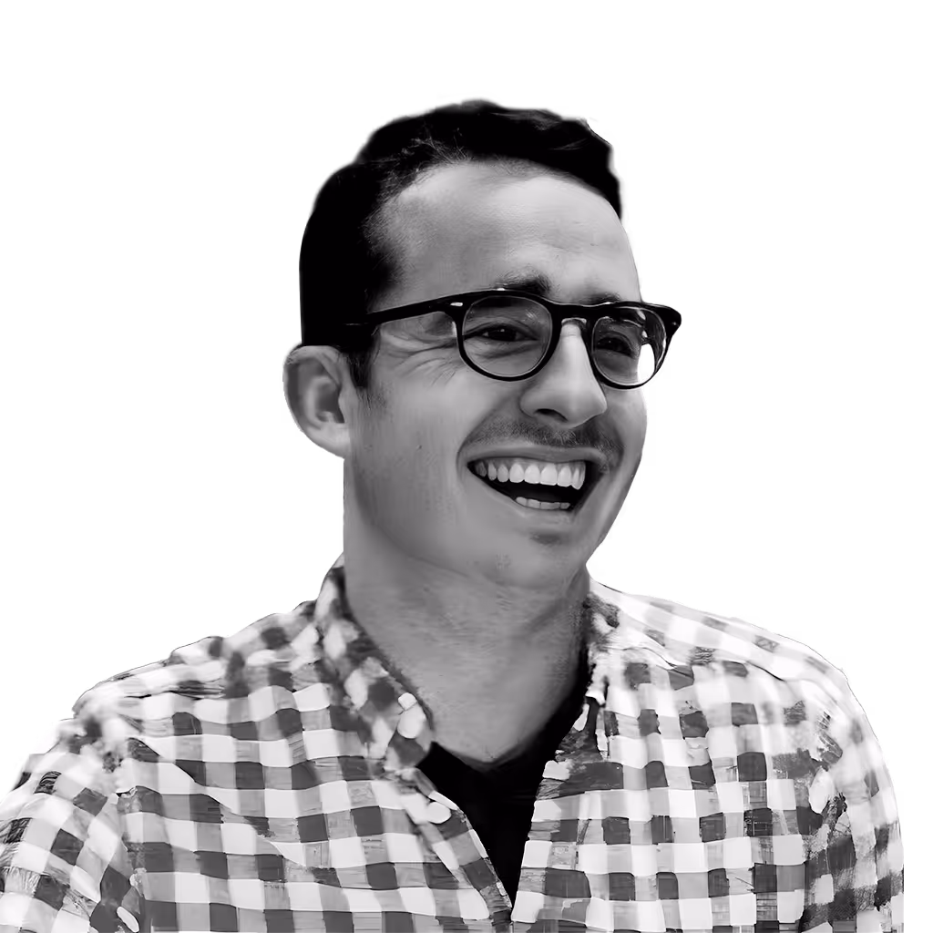 Smiling man with glasses wearing a checkered shirt.