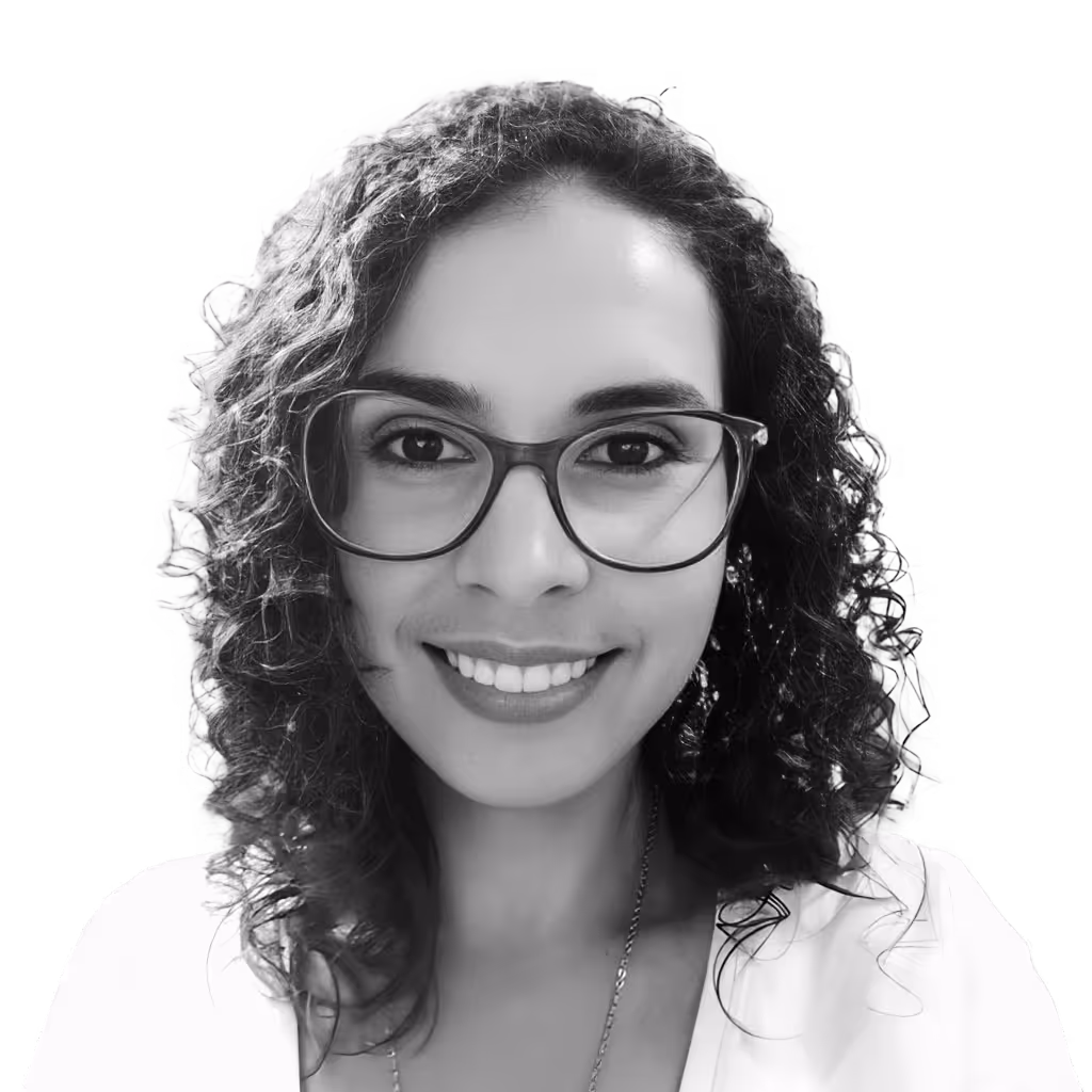 Smiling woman with curly hair wearing glasses and a white top, against a transparent background.