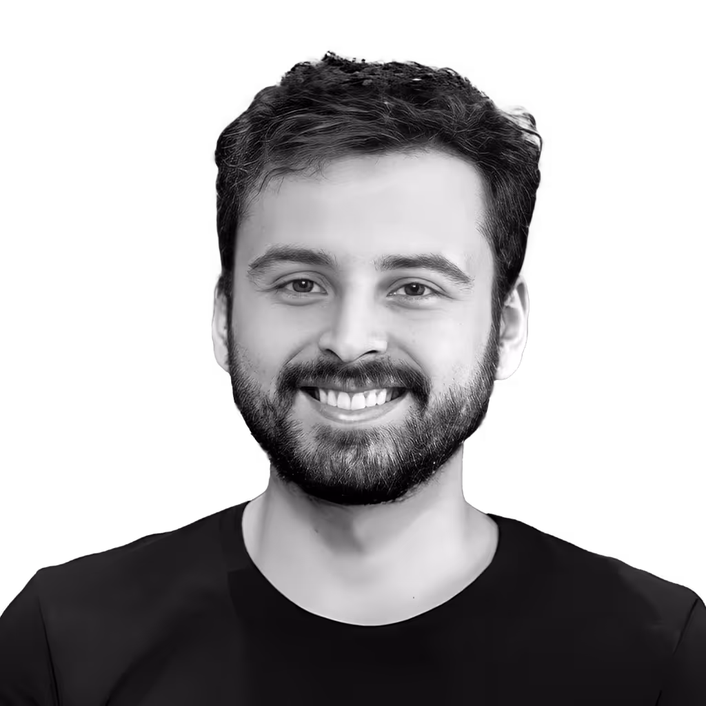 Smiling man with dark hair and beard wearing a black shirt on a transparent background.