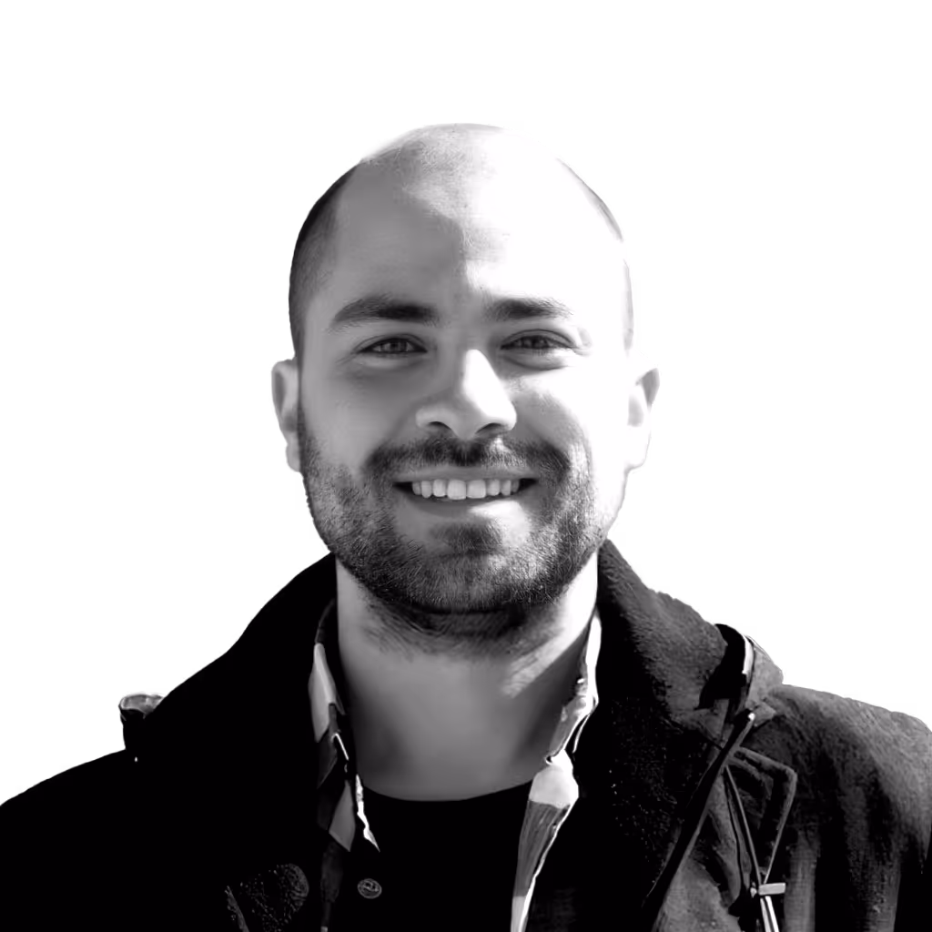 Smiling bald man with a beard wearing a dark coat and shirt.