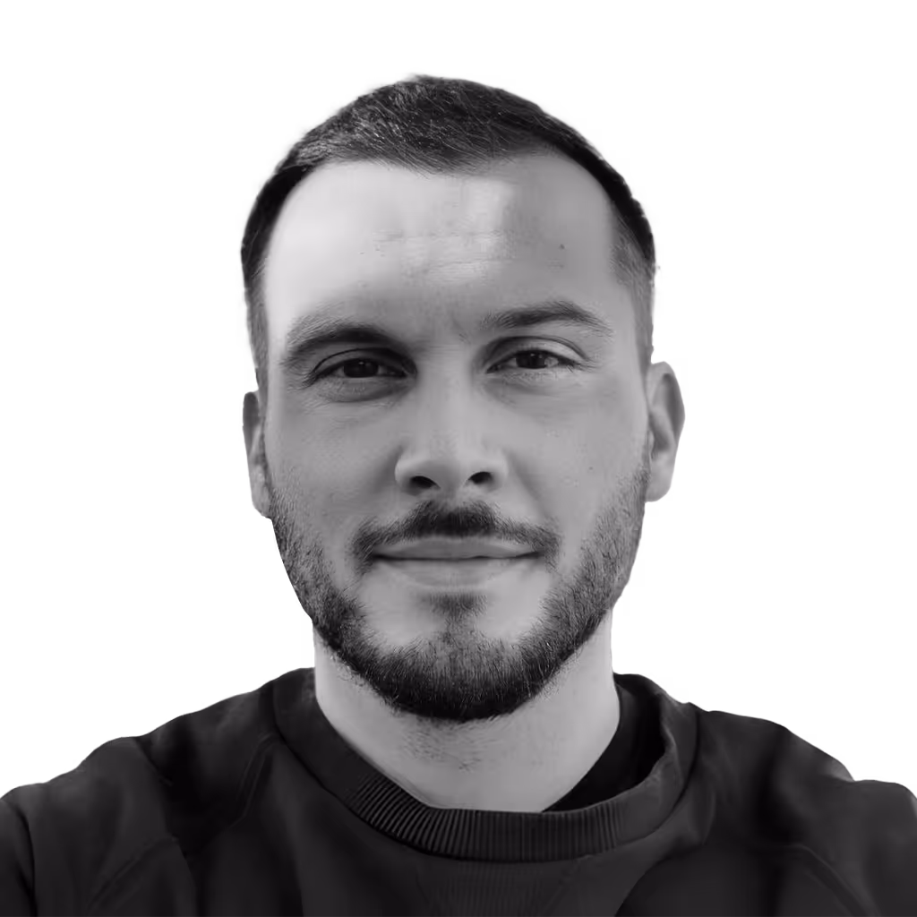 Close-up black and white portrait of a man with short hair and a beard, wearing a dark shirt.