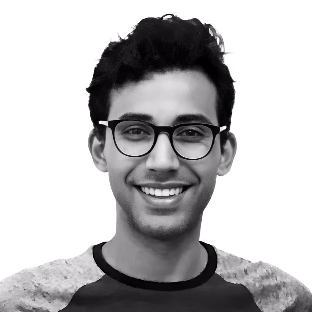 Young man with dark hair and glasses smiling at the camera.